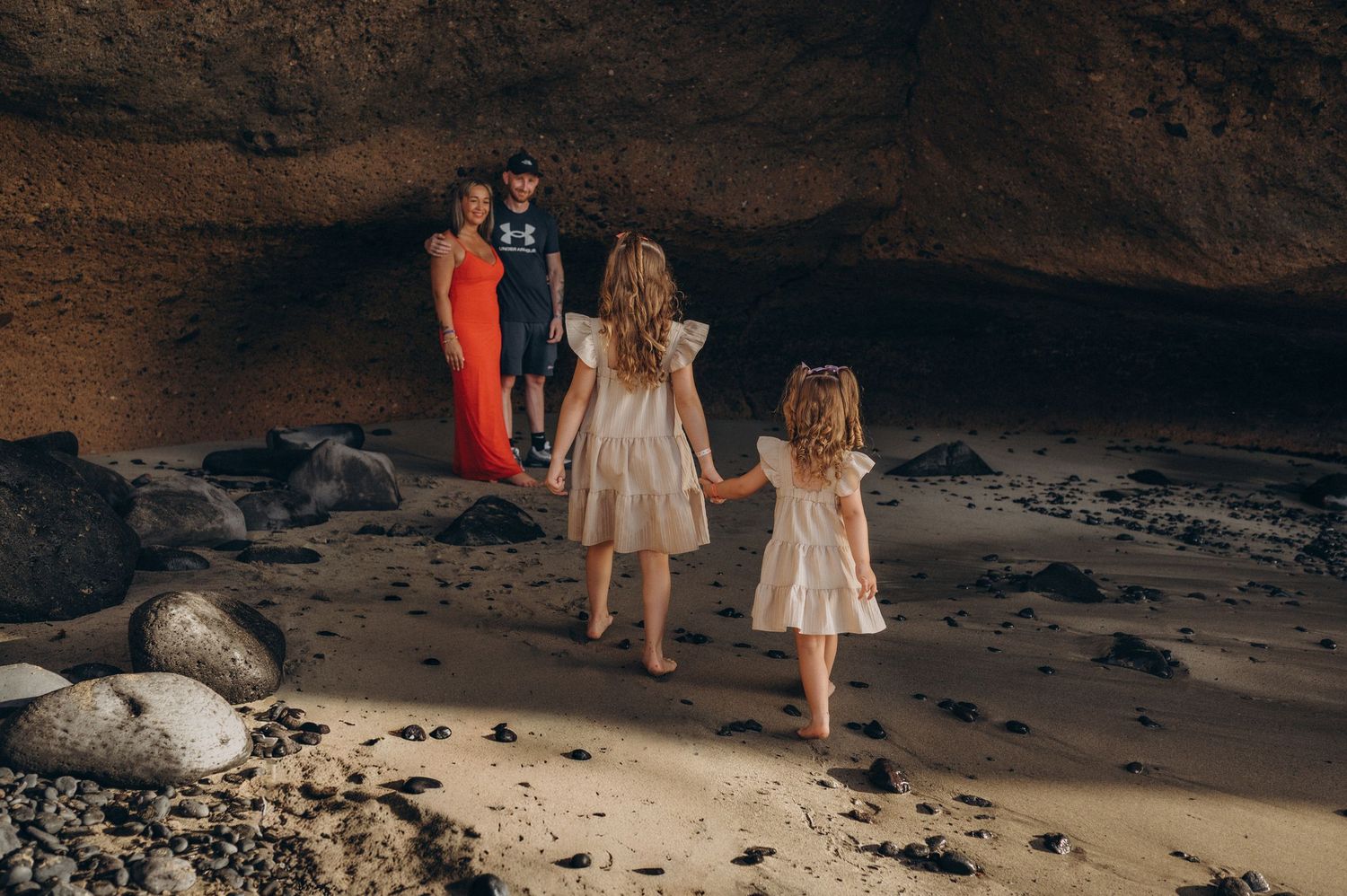 Girls walking hand in hand to their parents during family photoshoot on Tenerife coast