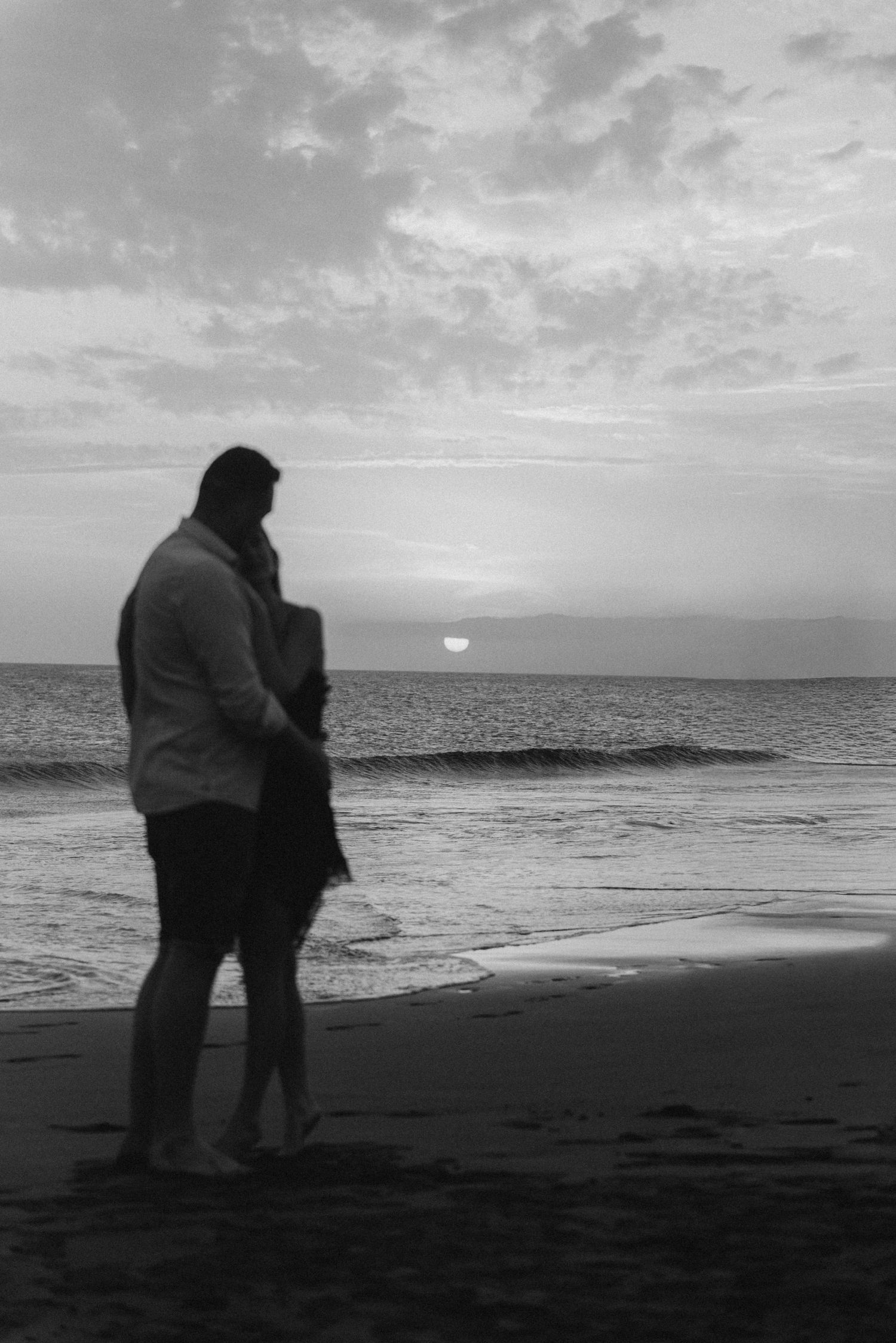 Couple embracing and enjoying the view of Montaña Roja and ocean on Playa de La Tejita, Tenerife