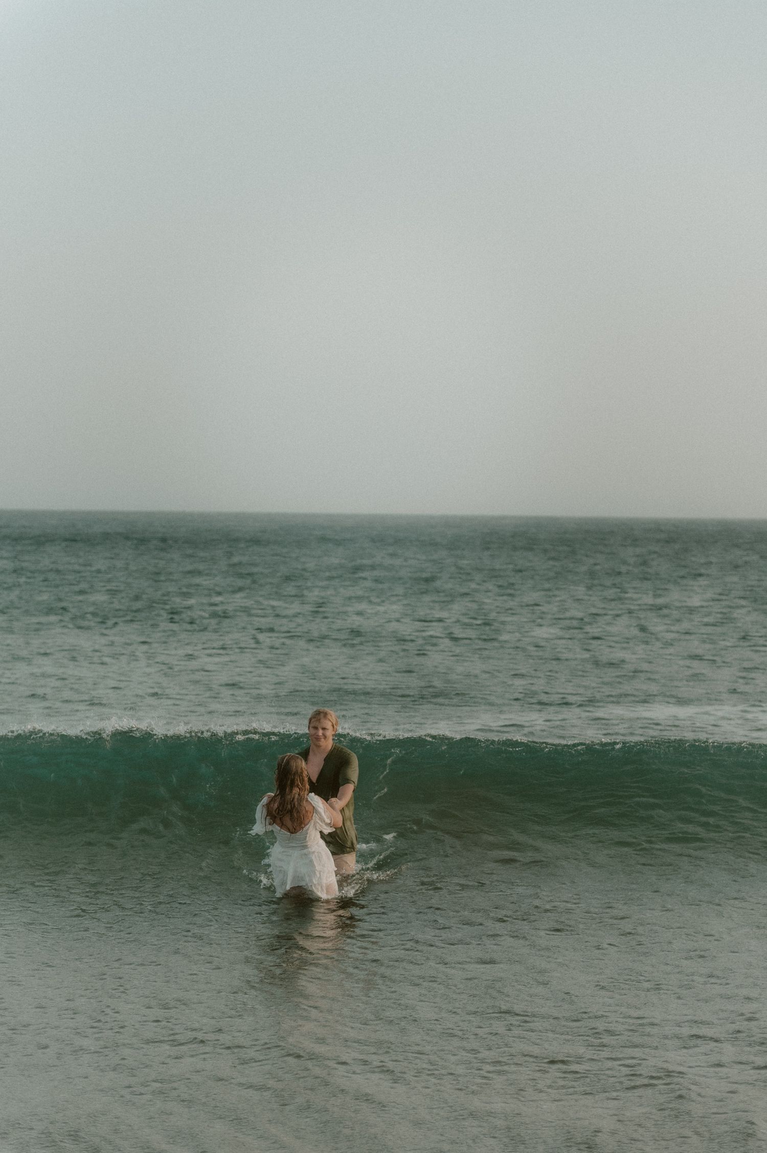 Couple standing in an ocean wave at Playa Tejita, Tenerife couples photoshoot