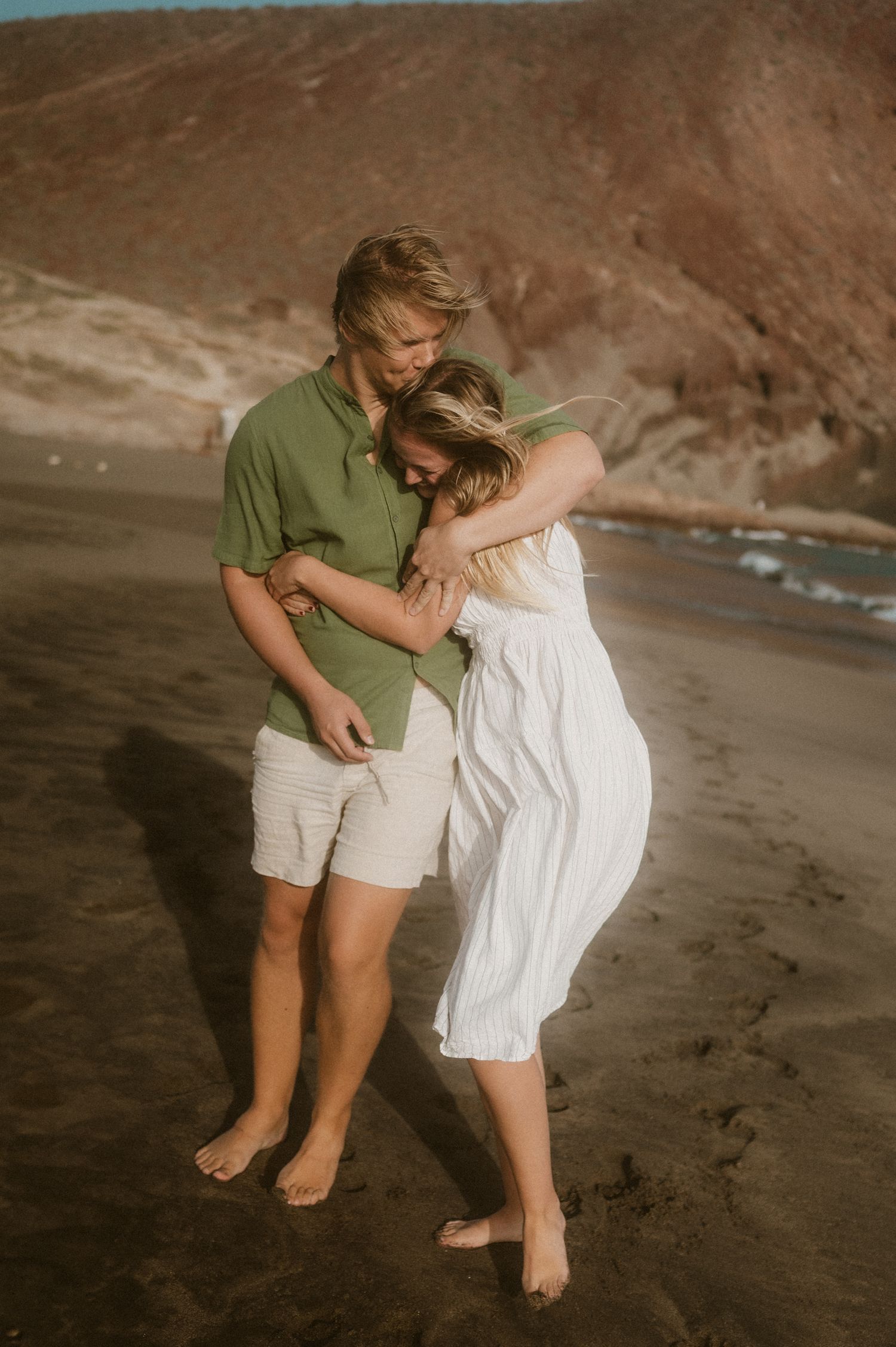 Young couple cuddling and snuggling barefoot in the sand at Playa Tejita, Tenerife couples photoshoot