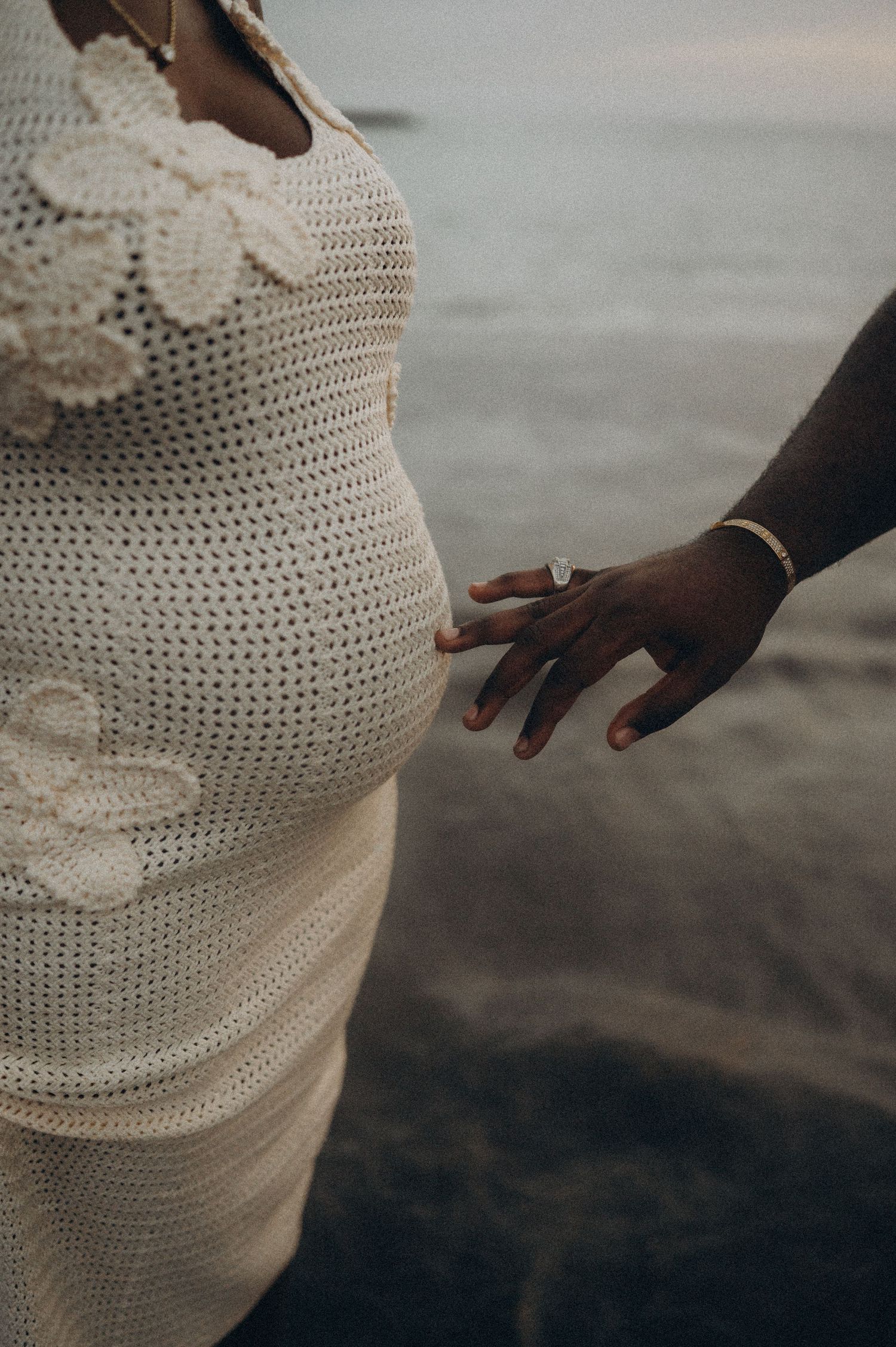 Close-up of man gently caressing pregnant belly in elegant dress