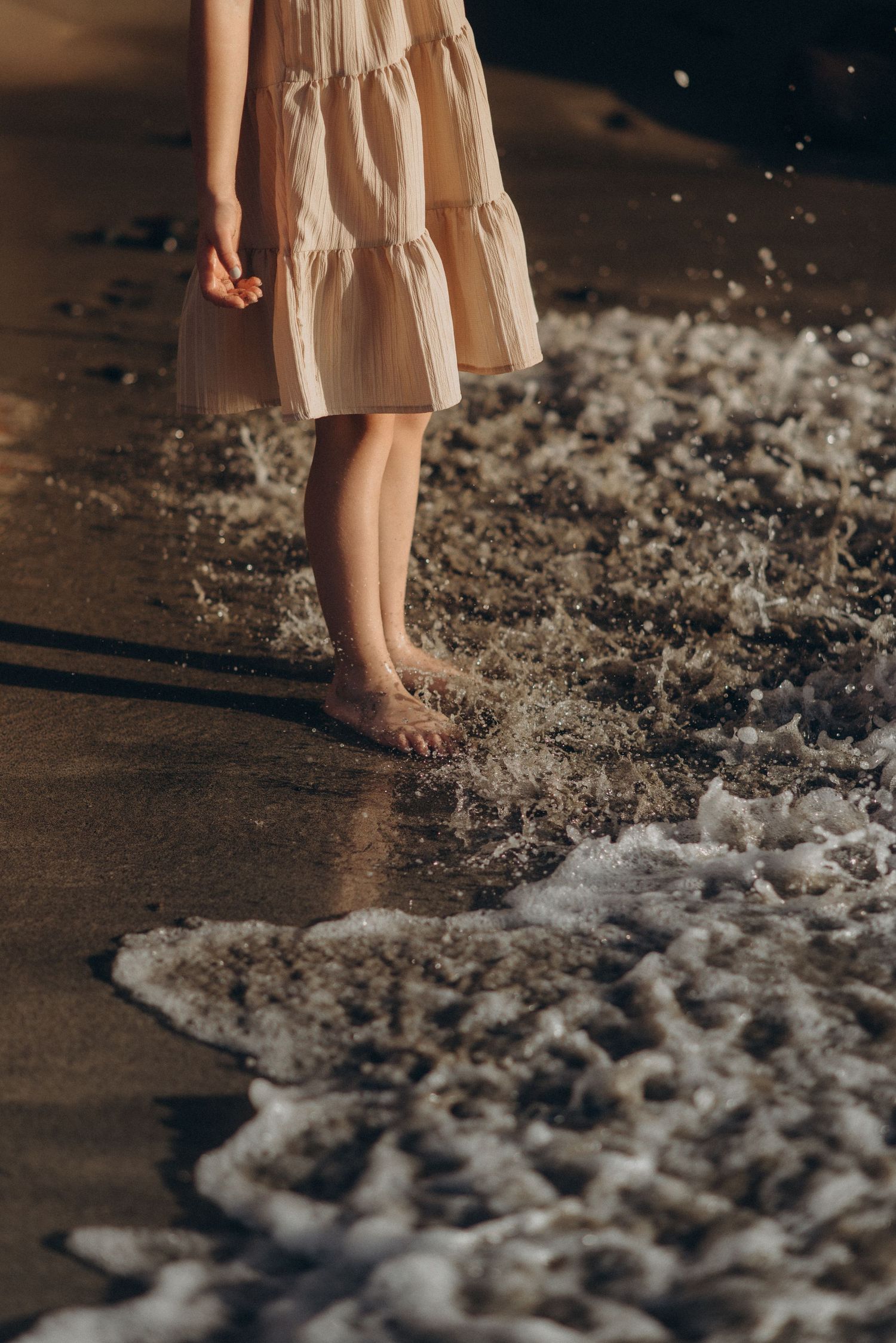 Close up of little girl's feet in sand with gentle ocean waves at Playa Morteros, Tenerife