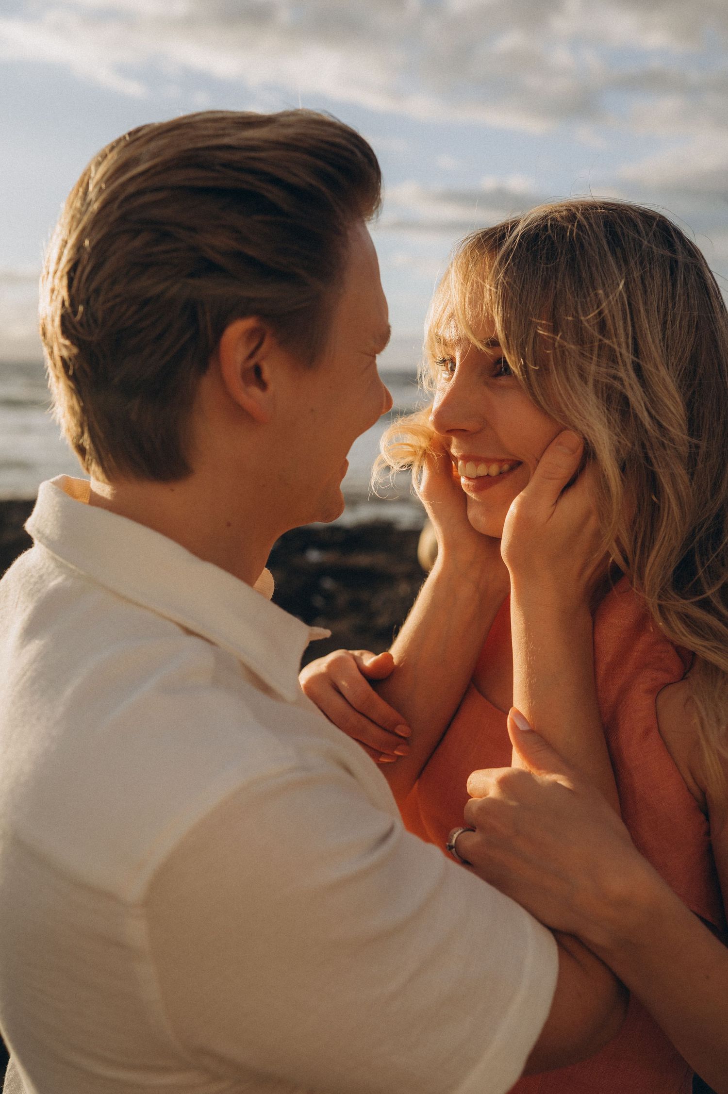 Parents embracing at sunset facing each other with ocean in background, Las Americas Tenerife