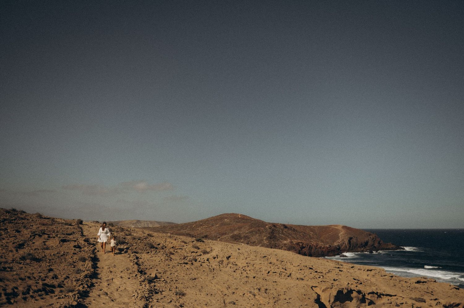 Family moment with mother and child walking along beach near Montaña Roja