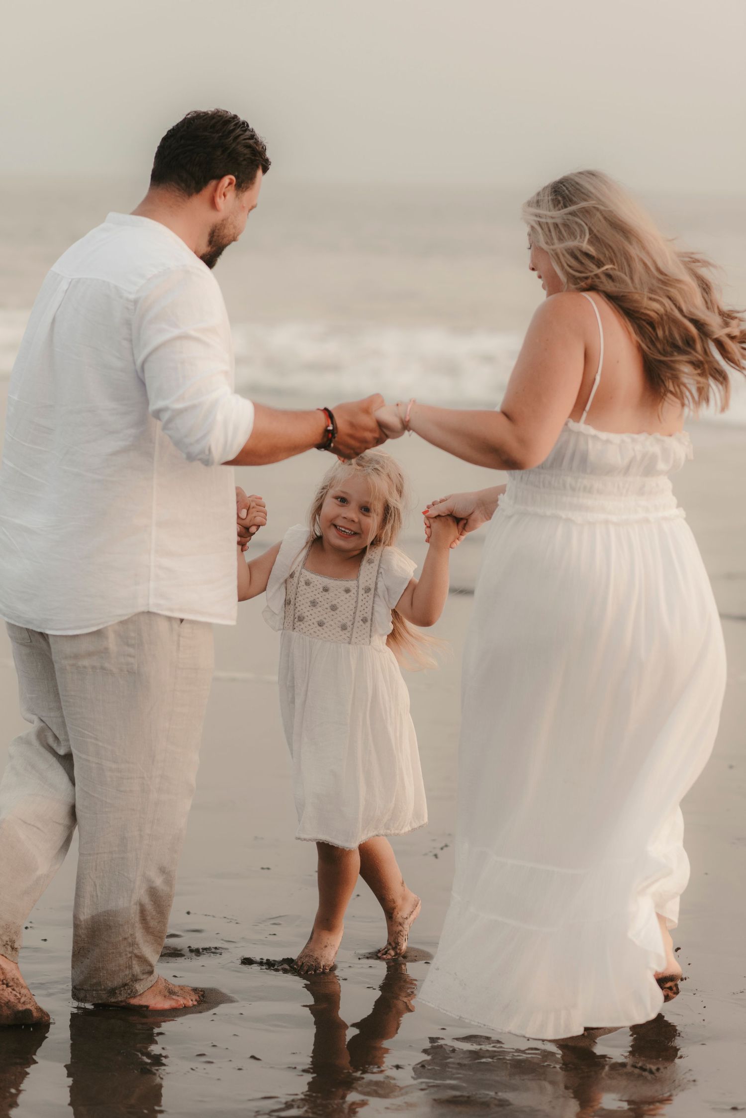 oyful family moment: parents and daughter dancing on Playa de la Tejita beach