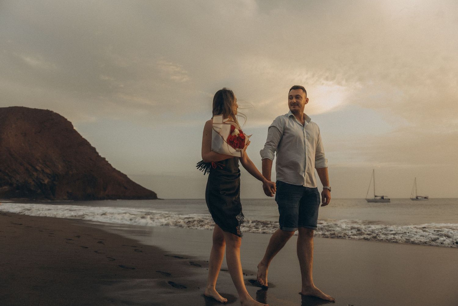 Romantic couple strolling on Playa de La Tejita beach near Montaña Roja, Tenerife coastline