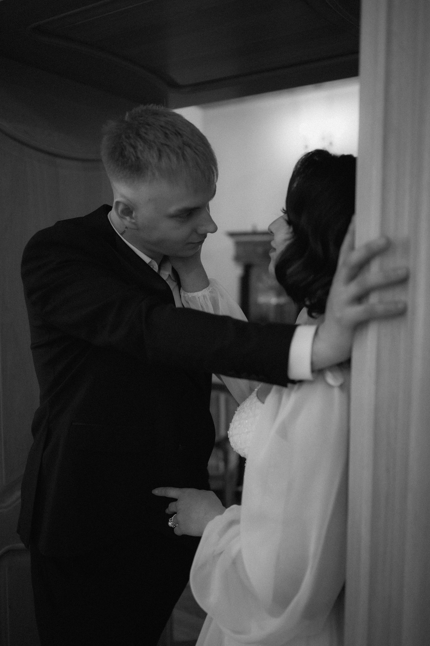 Black and white intimate portrait of the bride and groom standing close and looking at each other.