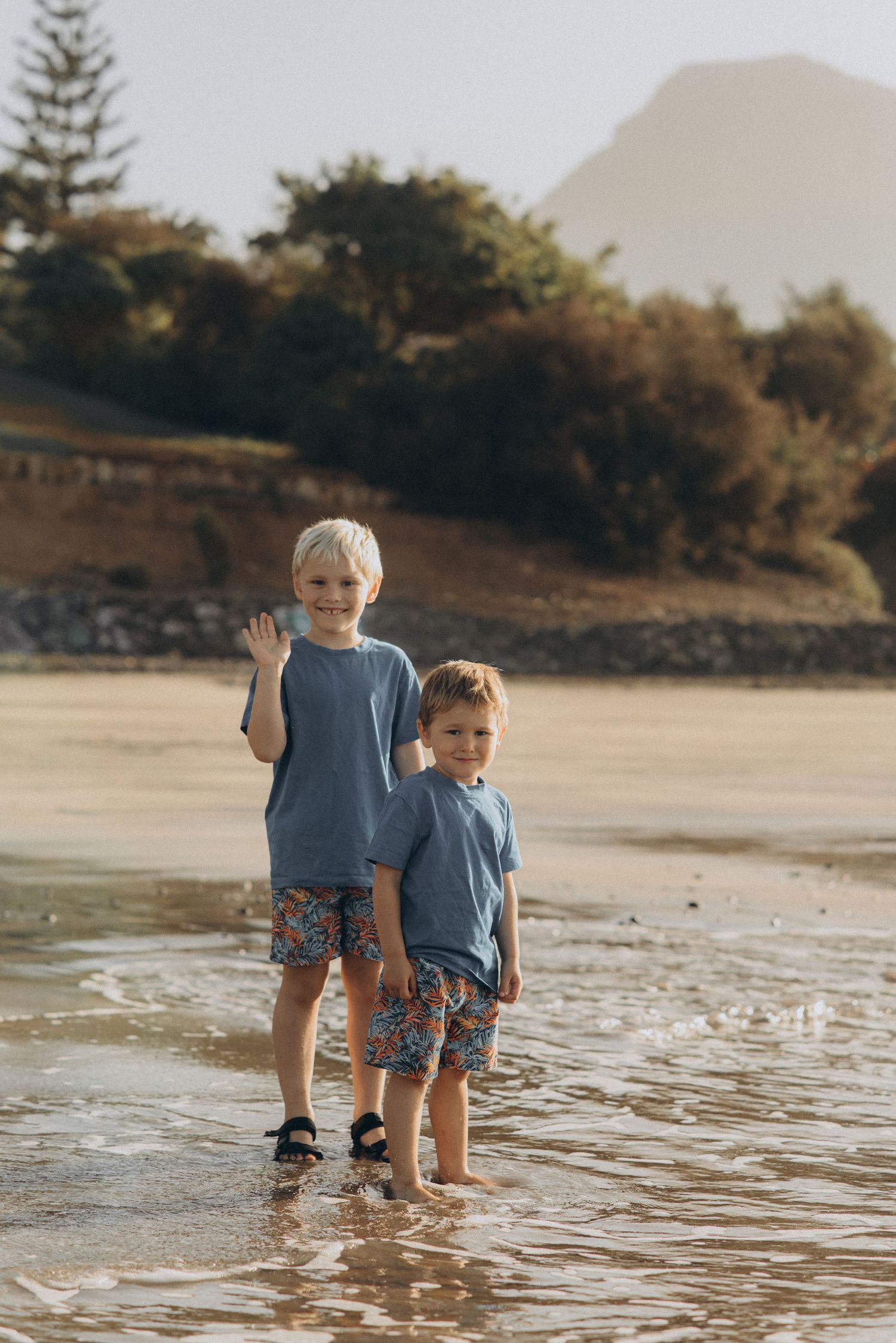 Playful moment of boys tossing stones into the sea while standing in shallow water at Playa Fañabé