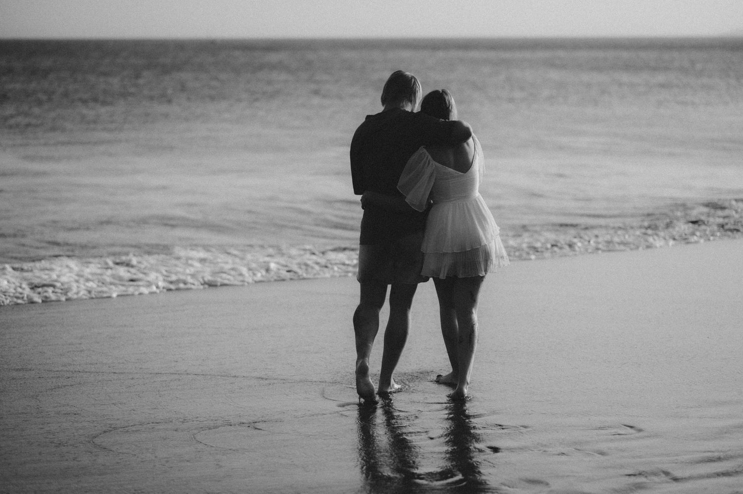 Couple leaning on each other while walking along Playa Tejita at sunset with ocean at their side, Tenerife couples photoshoot