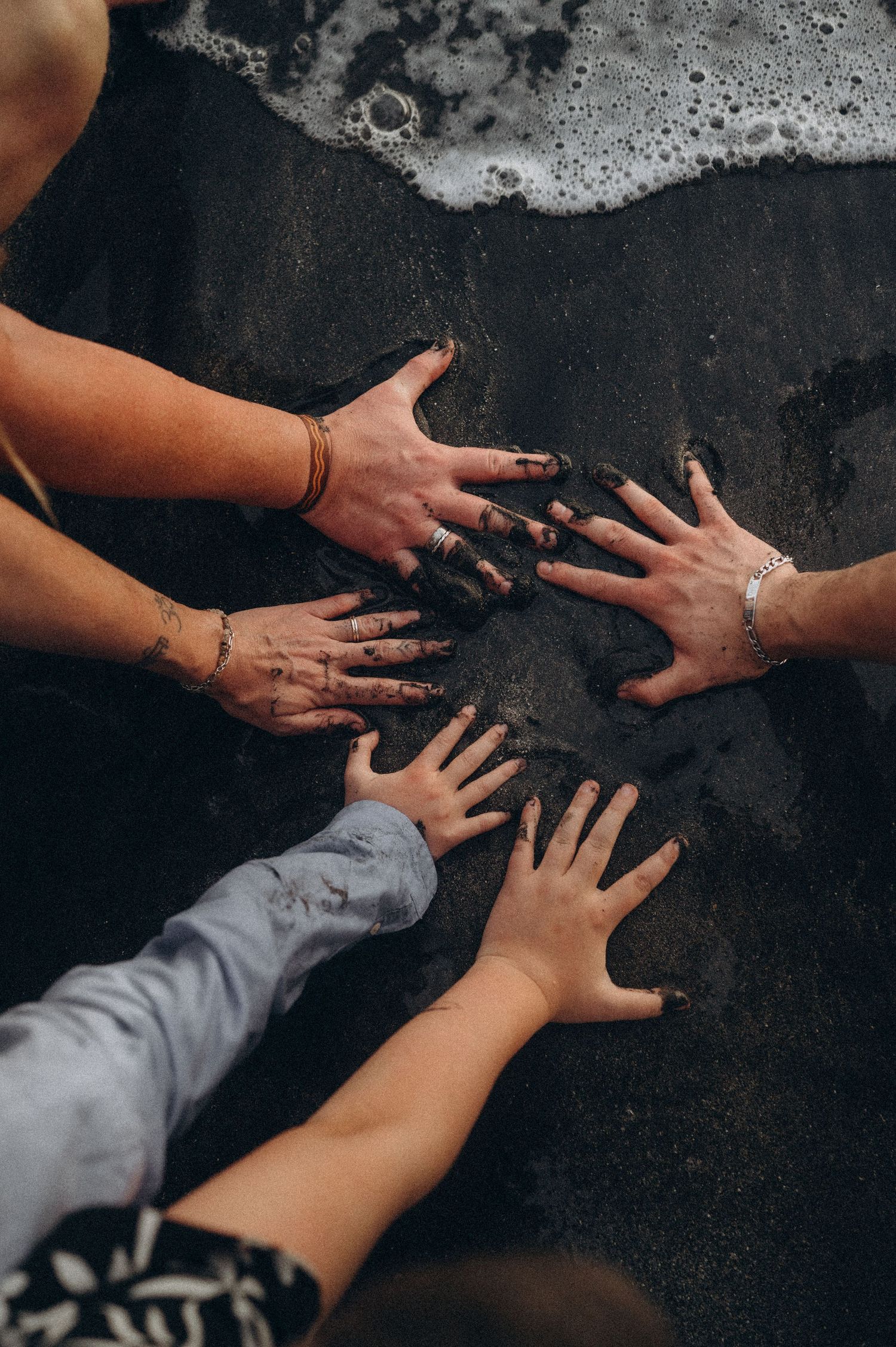 Family hand detail on sandy beach at Playa Fañabé, Tenerife coast