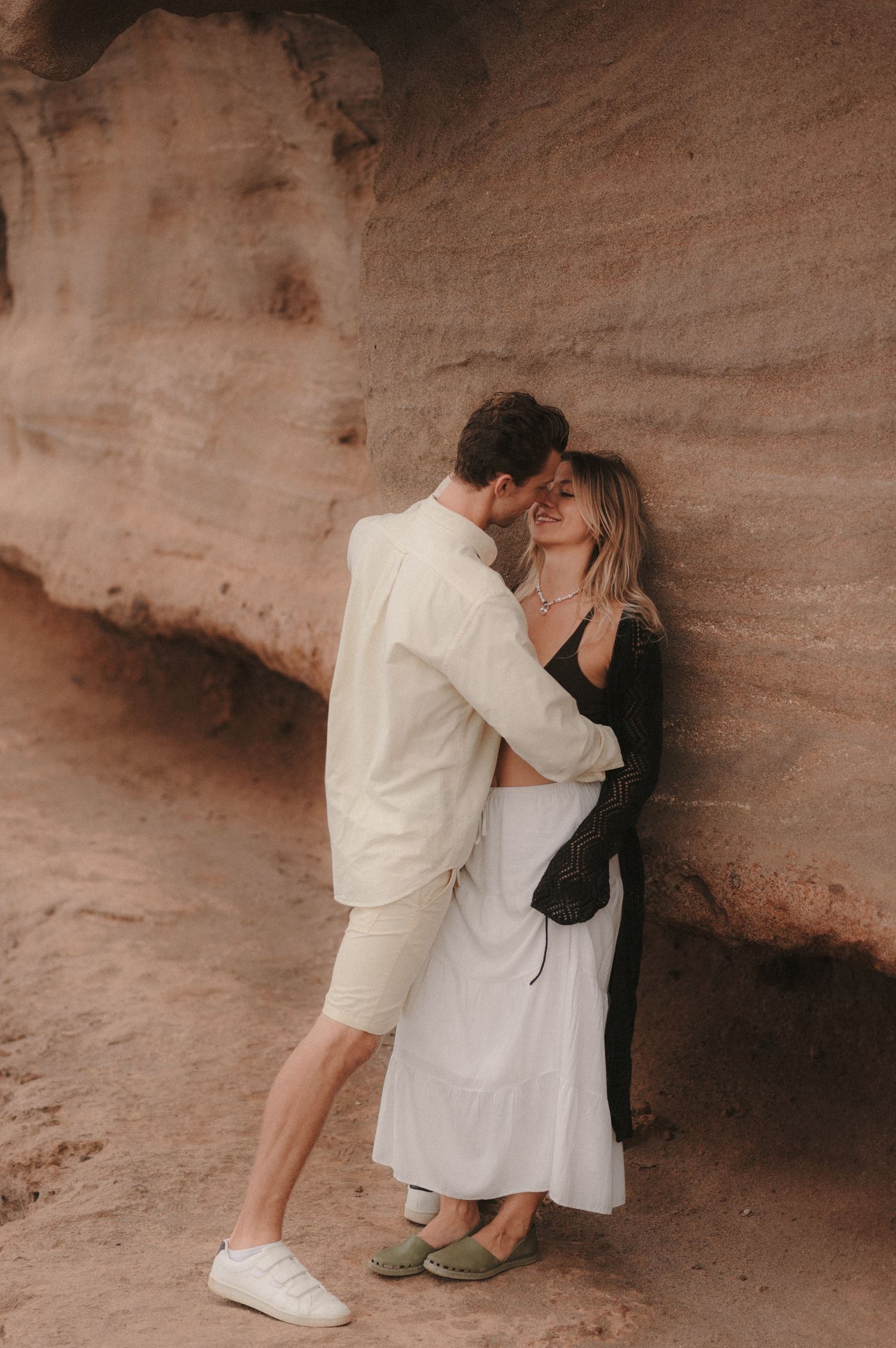 Romantic couple standing under a beautiful colorful cliff, enjoying a loving moment during a photoshoot in Tenerife