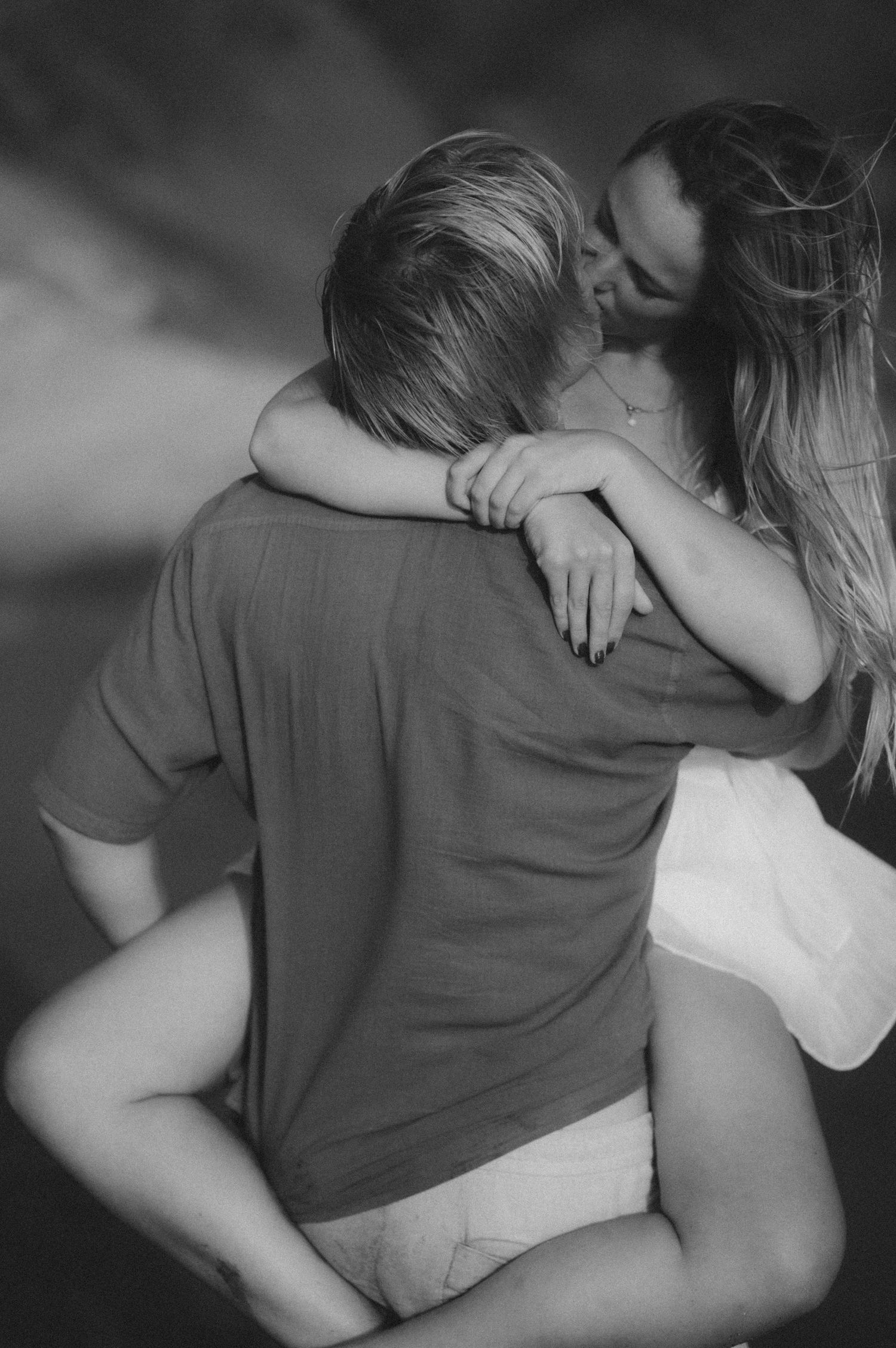 Man holding his partner in his arms while she kisses him, Playa Tejita couples photoshoot with ocean and Montaña Roja in the background