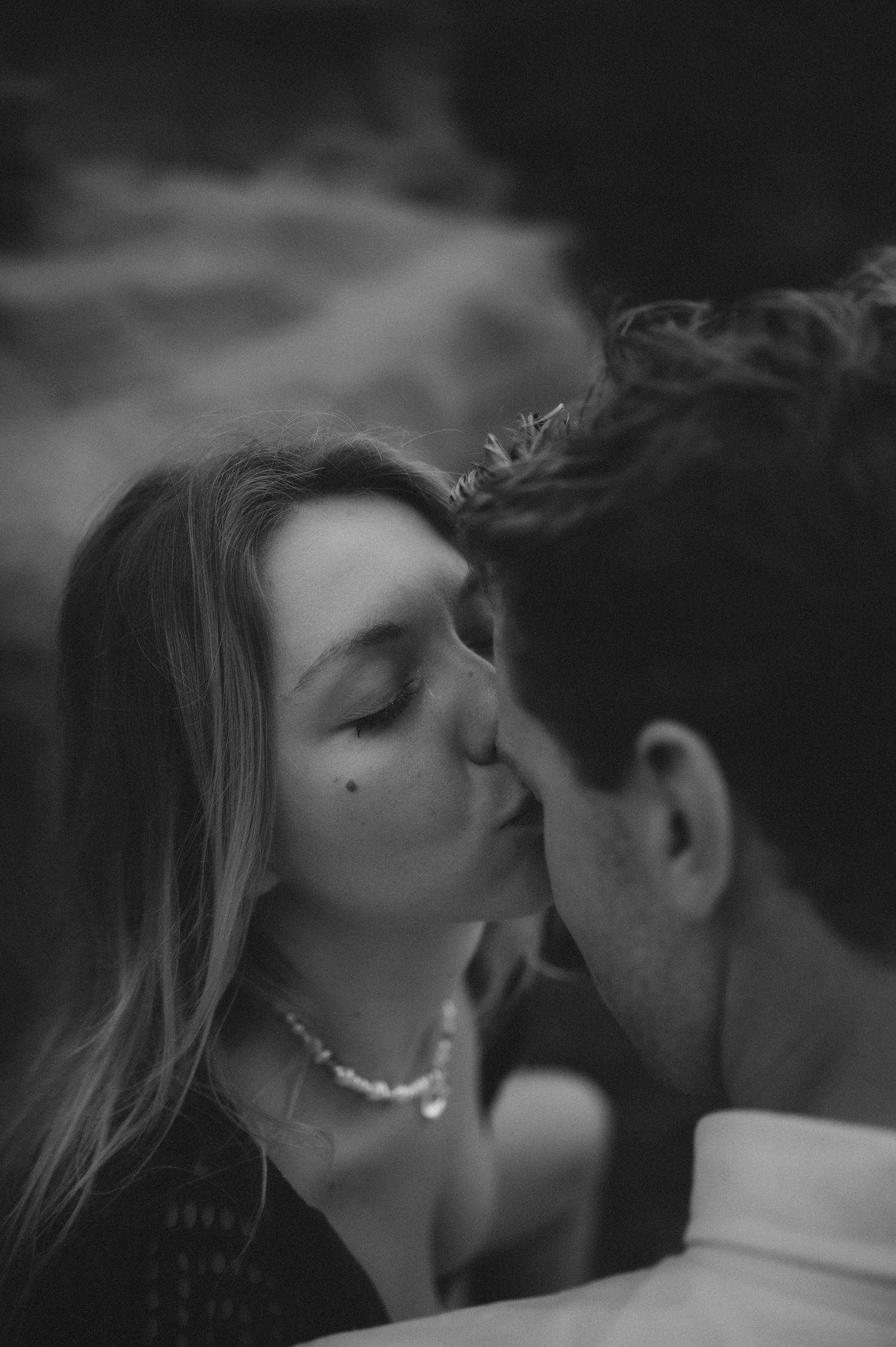 Woman gently kissing her partner on the forehead, romantic moment with ocean and cliffs in the background, Tenerife