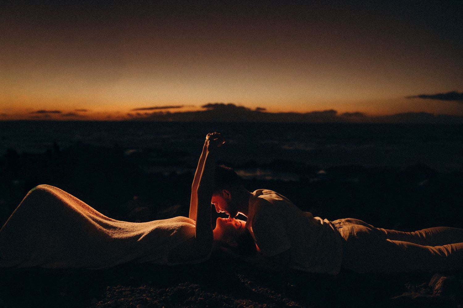 Intimate moment of couple looking into each other’s eyes with soft lights on south Tenerife beach