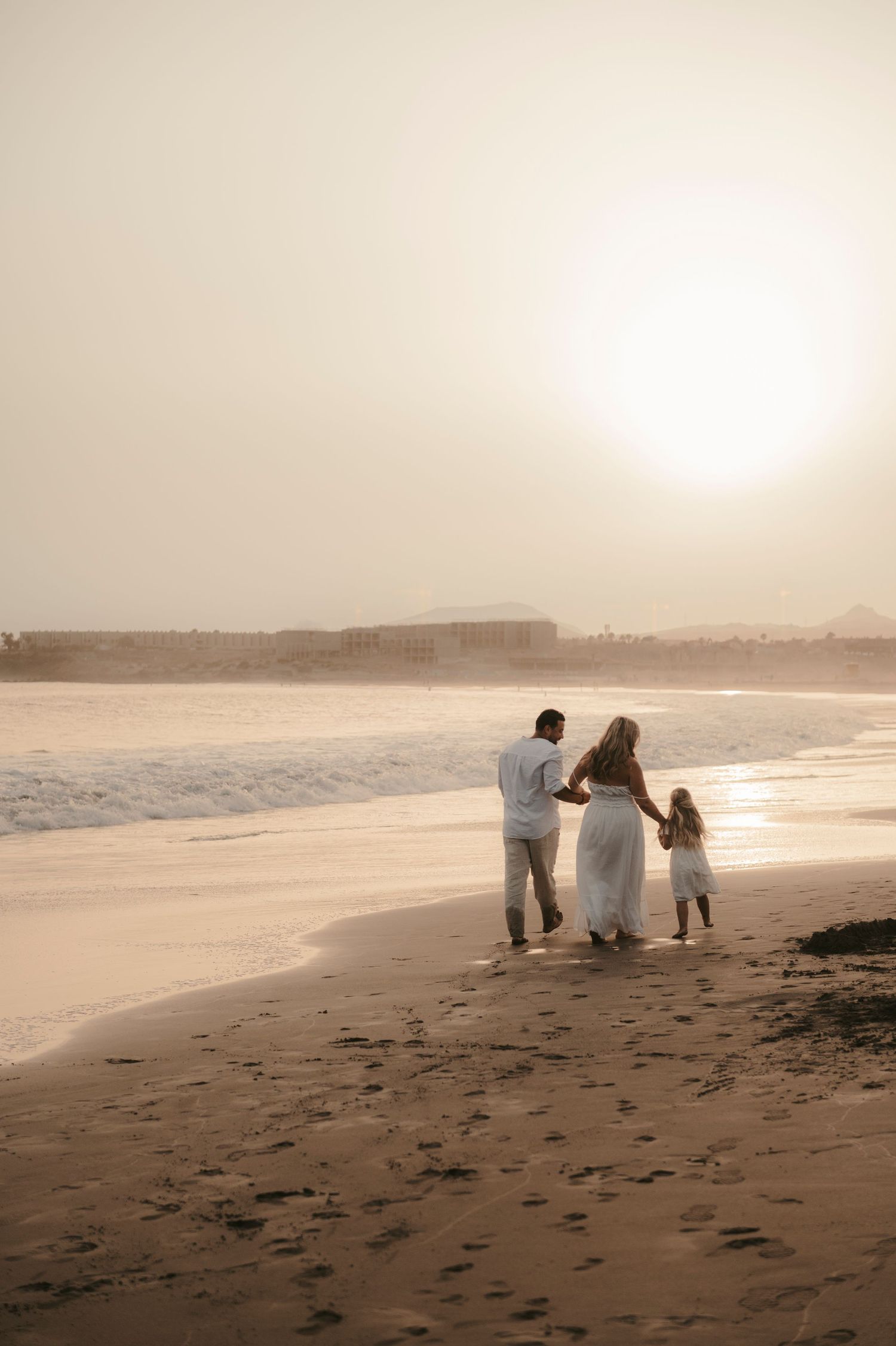 Long-distance shot of a family strolling by the ocean at sunset on Playa La Tejita