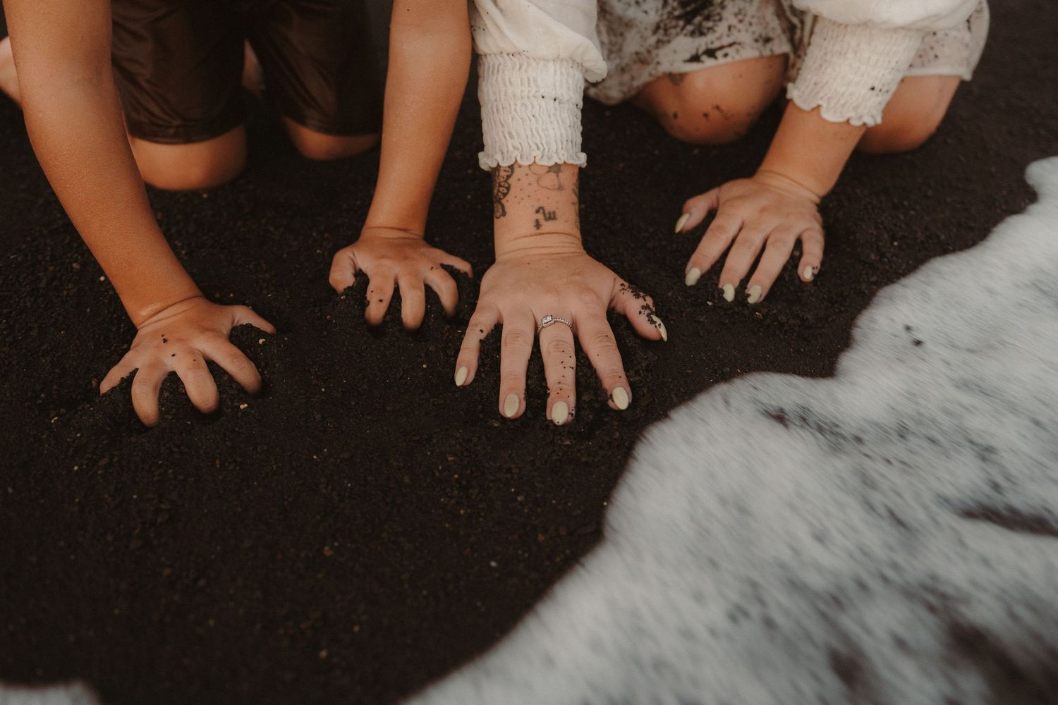 Tender moment of mother and child’s hands in sand with ocean wave, Tenerife photography