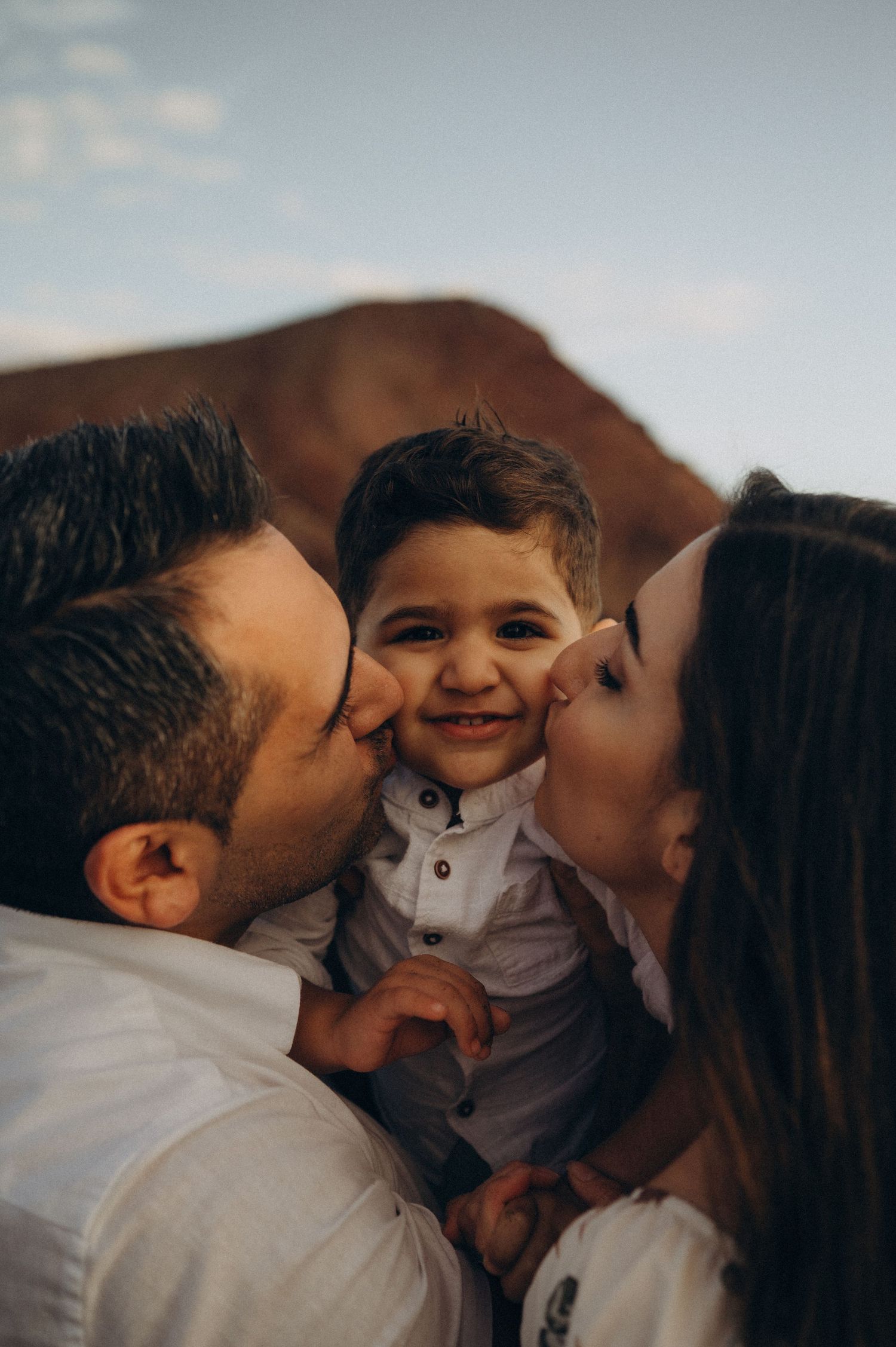 A tender family moment captured in a series of photos showing loving kisses and embraces between parents and child.