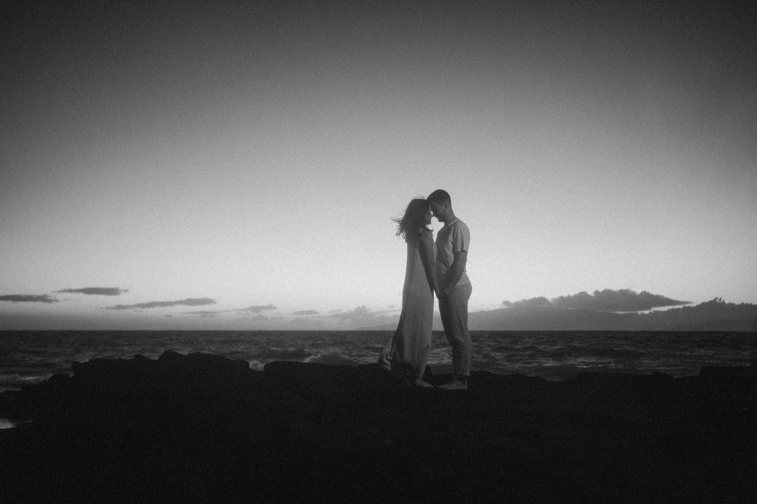 Silhouetted couple sharing intimate moment against dramatic sunset over Tenerife mountain landscape