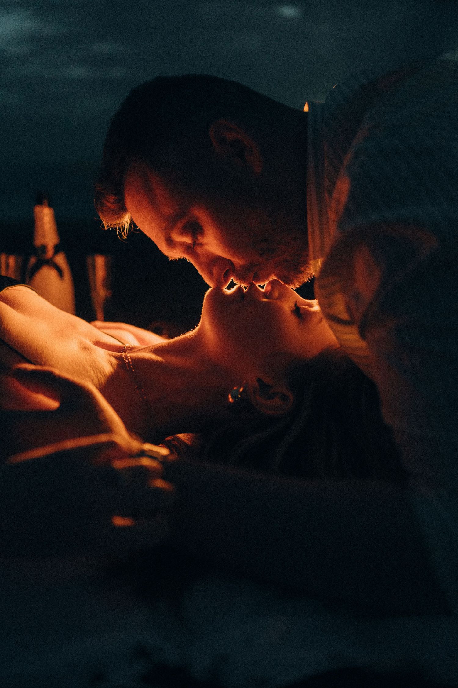 Young couple sharing tender kiss while lying together on Playa de La Tejita, Tenerife at night