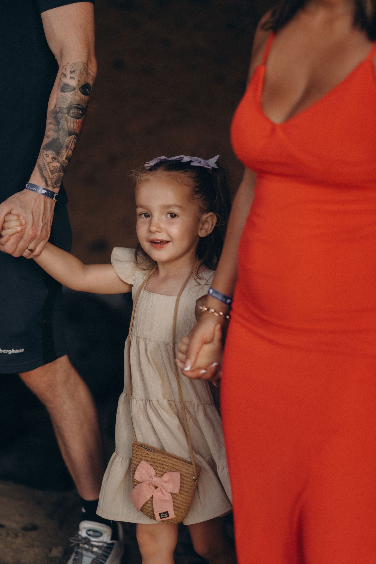 Little daughter walking hand in hand with parents during family moment in Tenerife