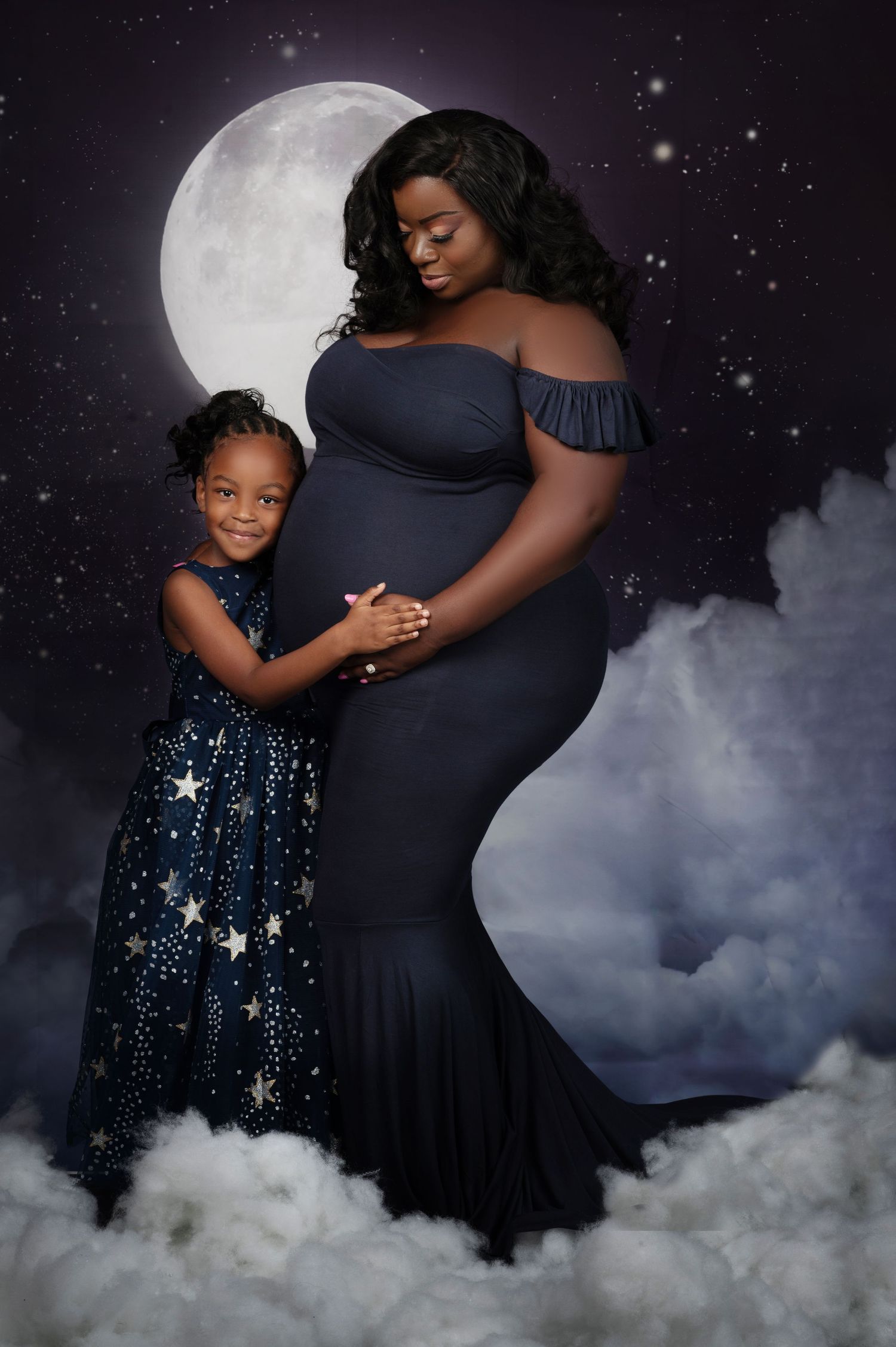 Dreamy nighttime maternity photo with starry backdrop and full moon.