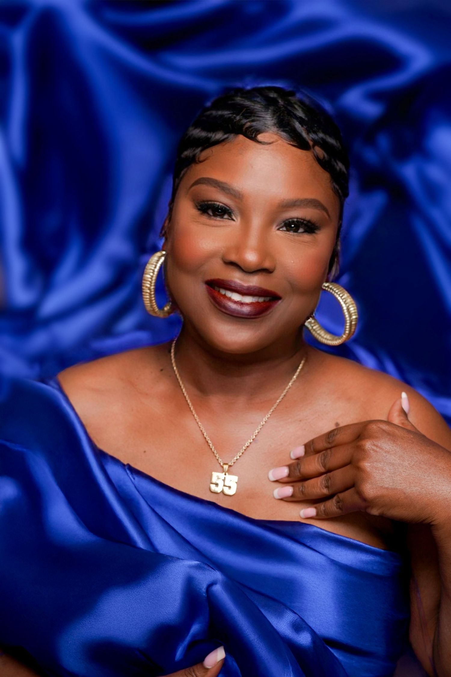 Elegant Senior portrait in royal blue satin with gold jewelry against blue textured background in Saint Petersburg Florida.