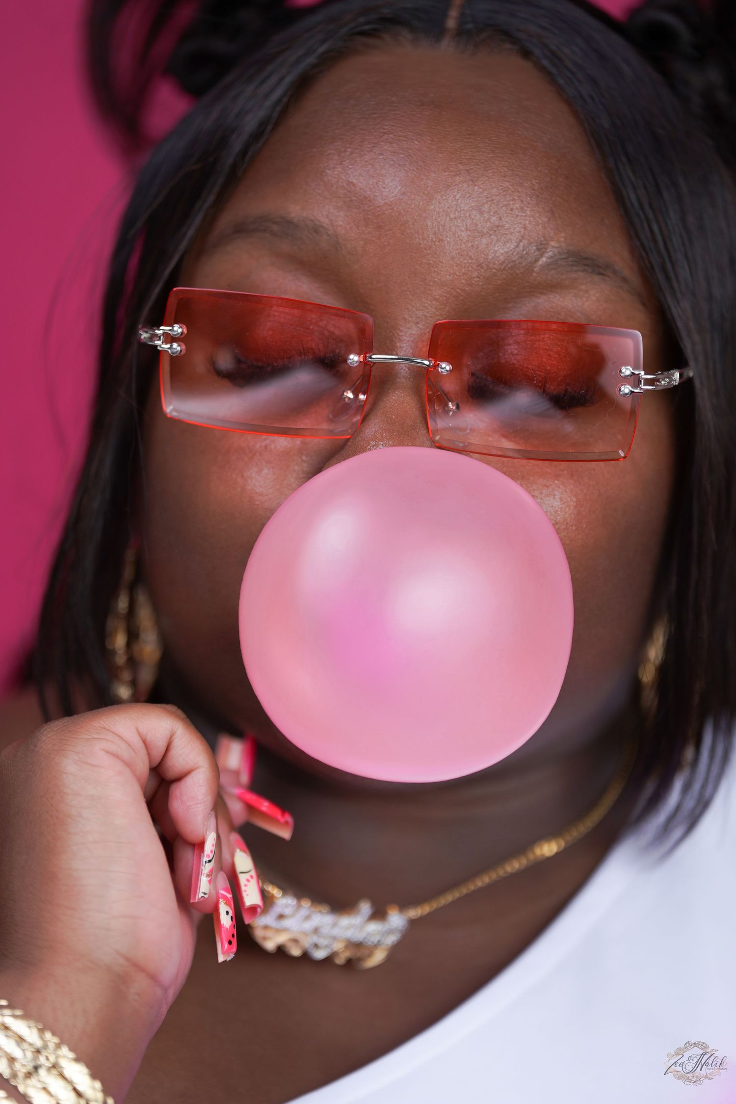 Playful portrait series with pink bubblegum and red-tinted glasses against magenta background in Saint Petersburg Florida.