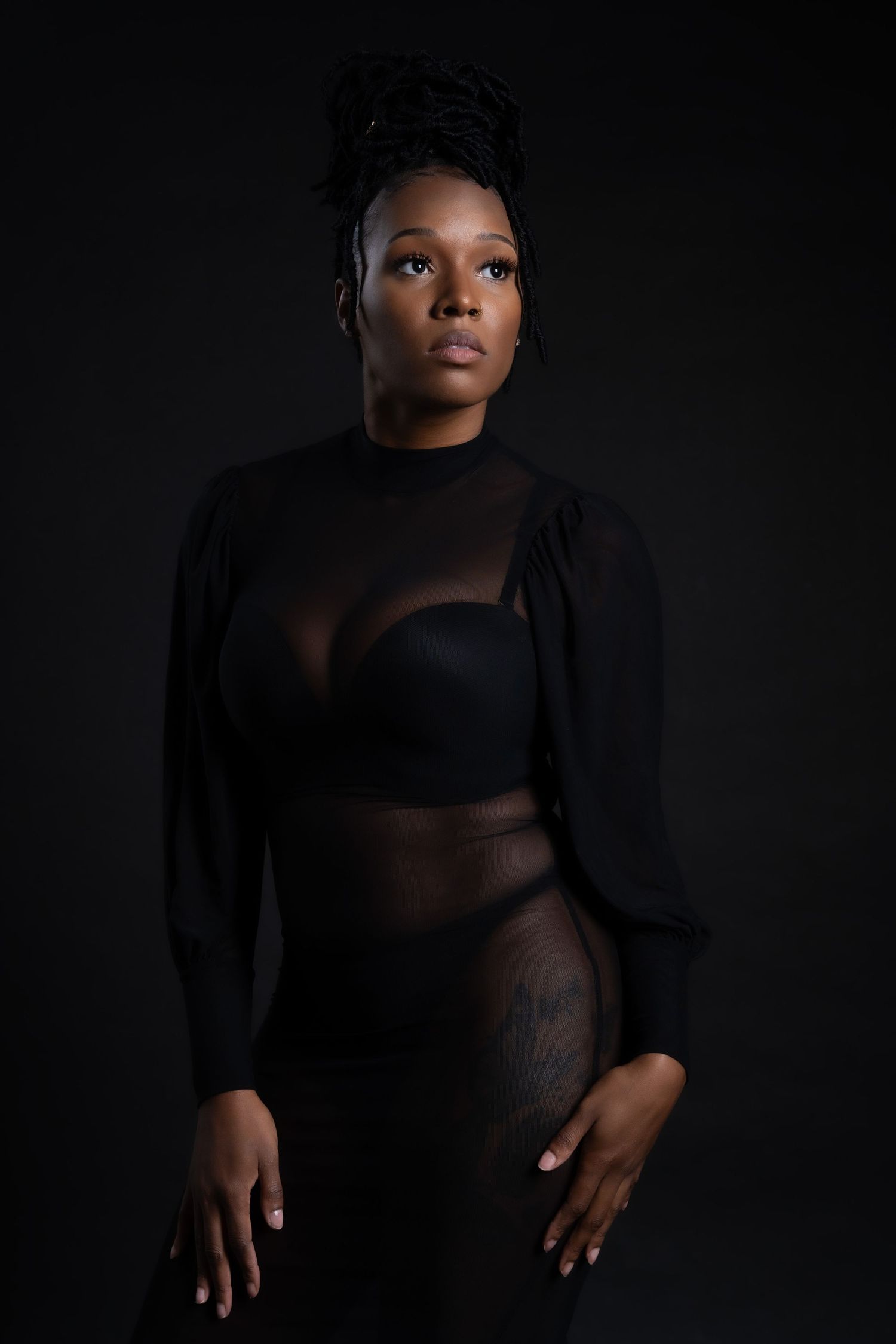 Moody portrait in sheer black long-sleeved outfit against dark background in Saint Petersburg Florida.