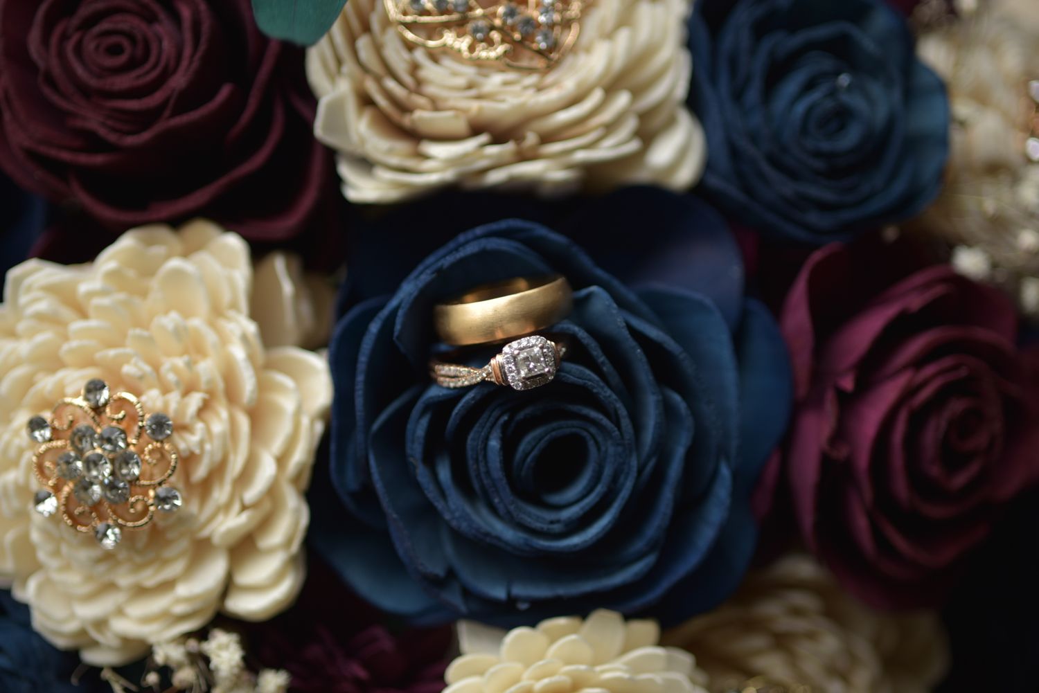 Elegant floral arrangement featuring burgundy, navy blue and cream roses with crystal embellishments.