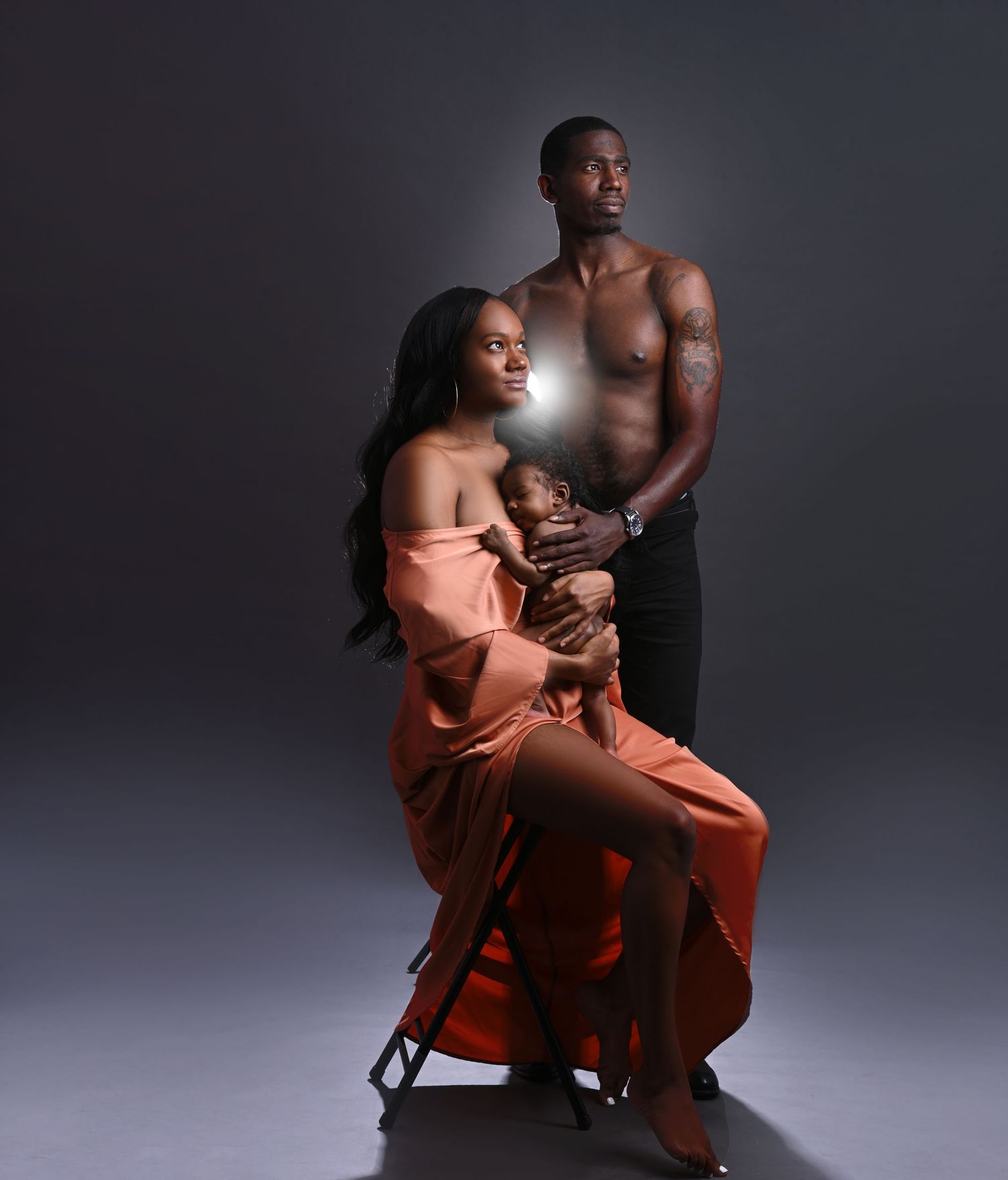 Artistic maternity studio session with dramatic lighting and coral dress.