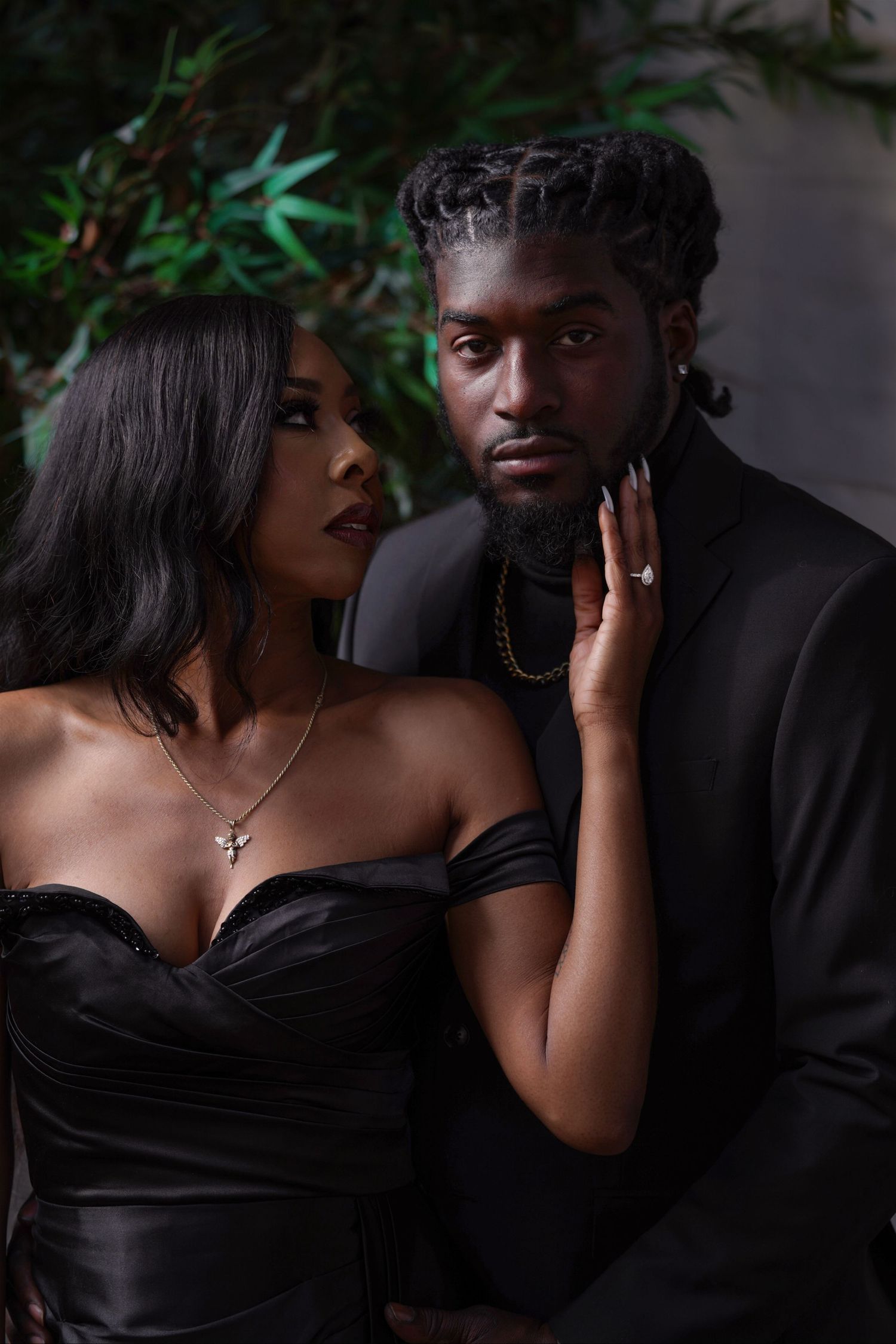 Intimate couples photoshoot in black attire against dark moody backdrop.