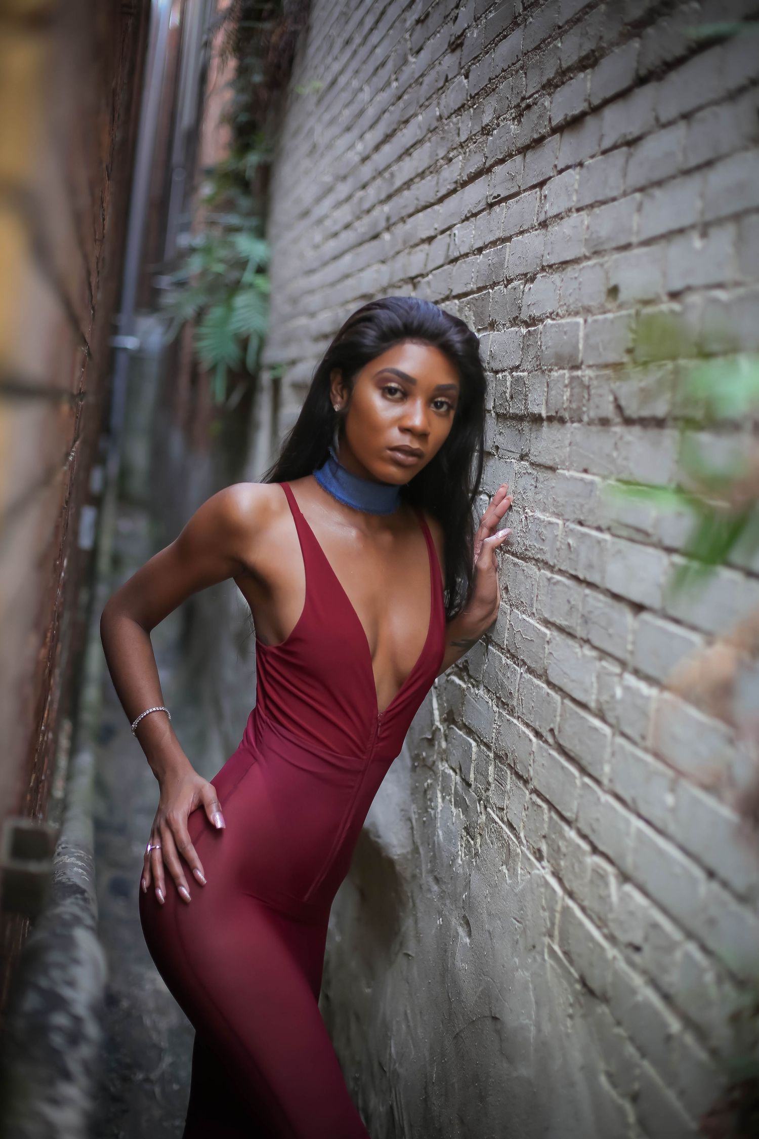 Fashion photoshoot against brick wall featuring burgundy evening gown in dynamic poses in Lakeland Florida.