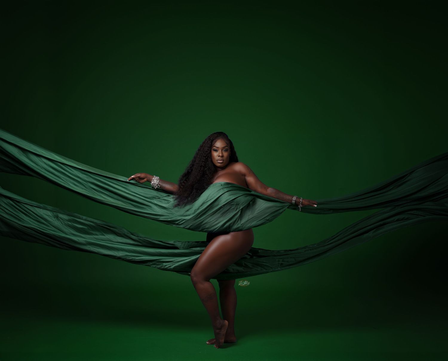 Artistic studio portraits with dark green fabric creating dramatic flowing lines against deep background in Saint Petersburg Florida.