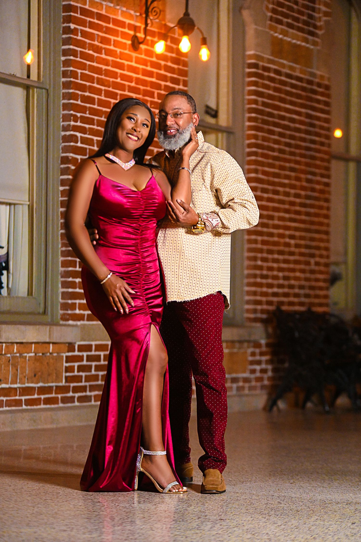 Couple poses for romantic photos in front of brick building with vintage lighting in Tampa Florida.