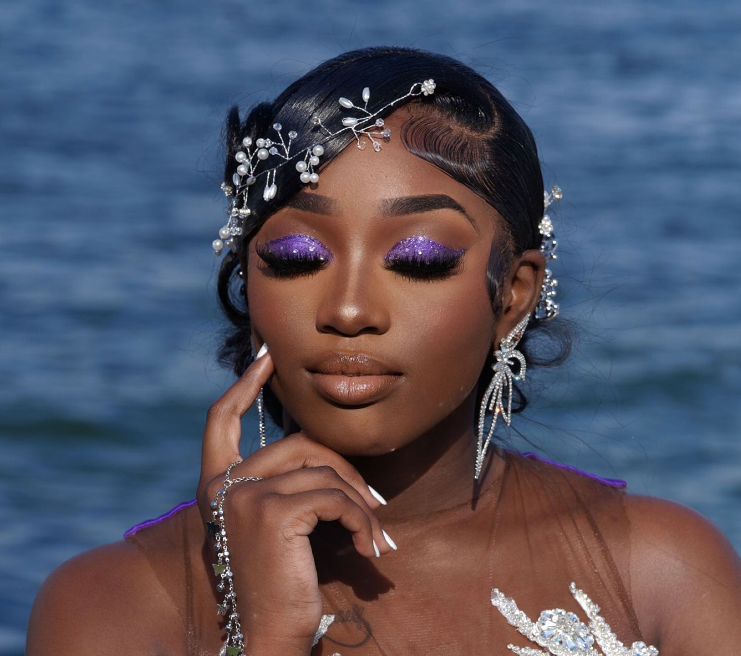 Beach portrait with sparkly accessories and purple eye makeup against ocean background in Saint Petersburg Florida.