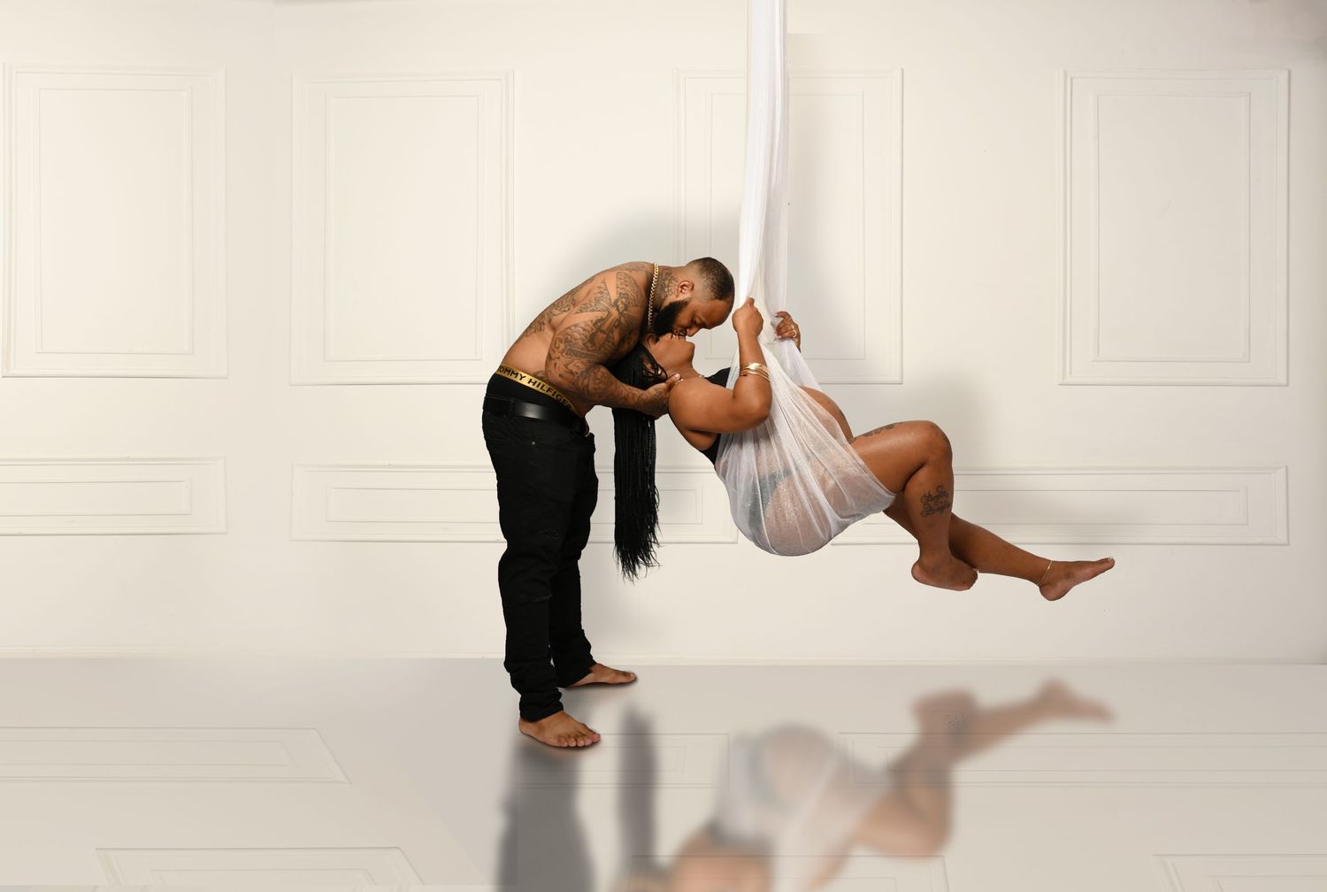 Artistic maternity photo series in white showing graceful movement and flowing fabric against light background.