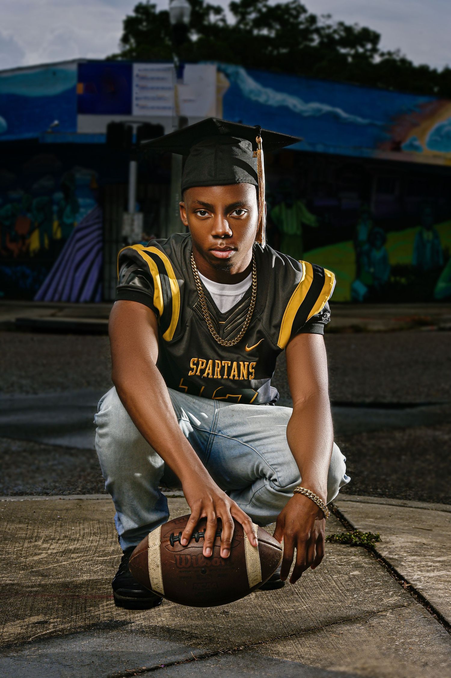 Athletic portrait series with football equipment in a Spartans uniform on concrete in Saint Petersburg Florida.