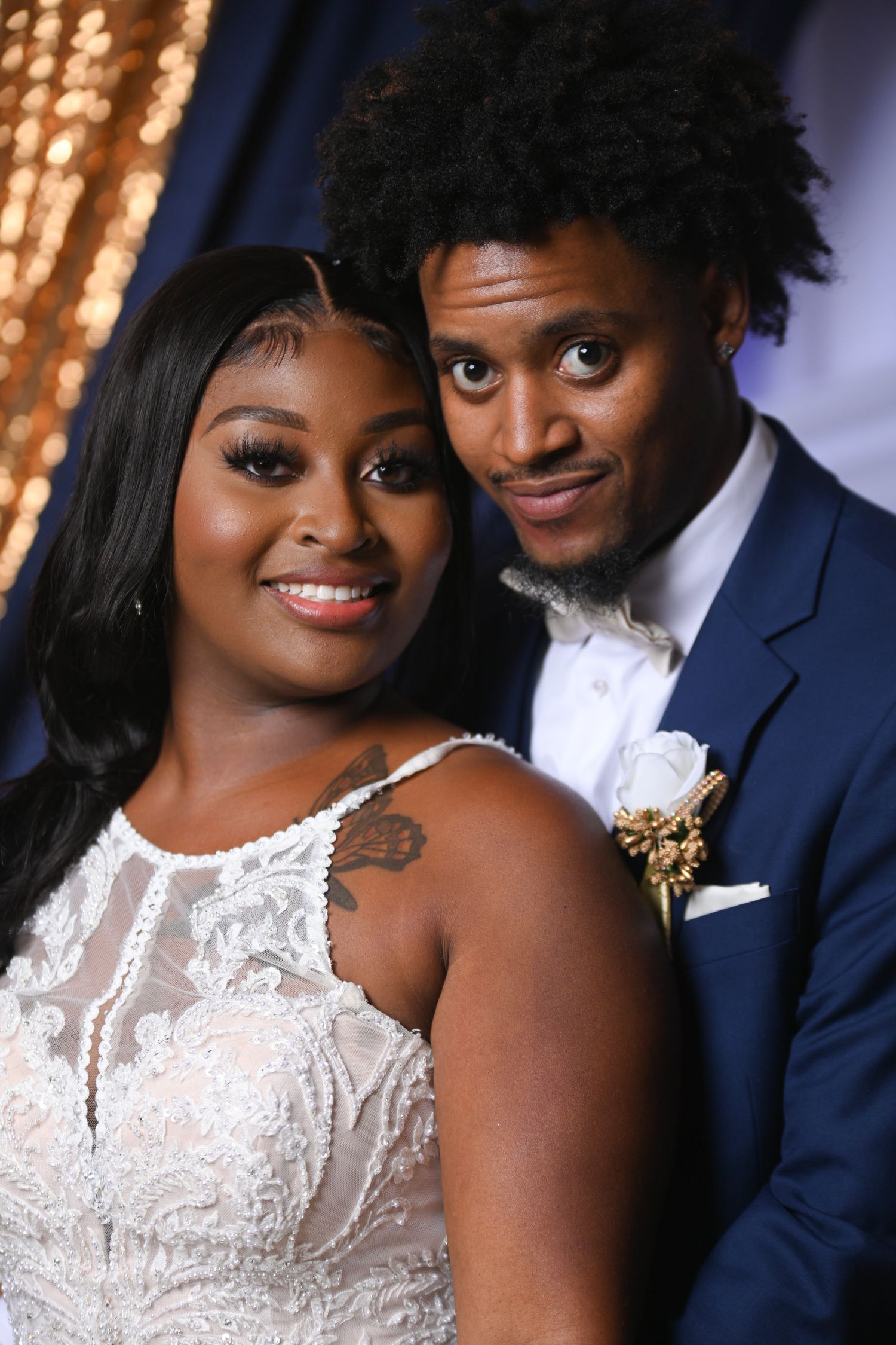 Elegant wedding portraits with sparkly backdrop showing couple in navy suit and white dress.