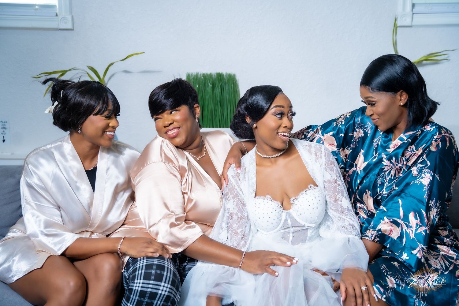 Wedding party members in coordinating outfits share joyful moments together in a casual indoor setting.