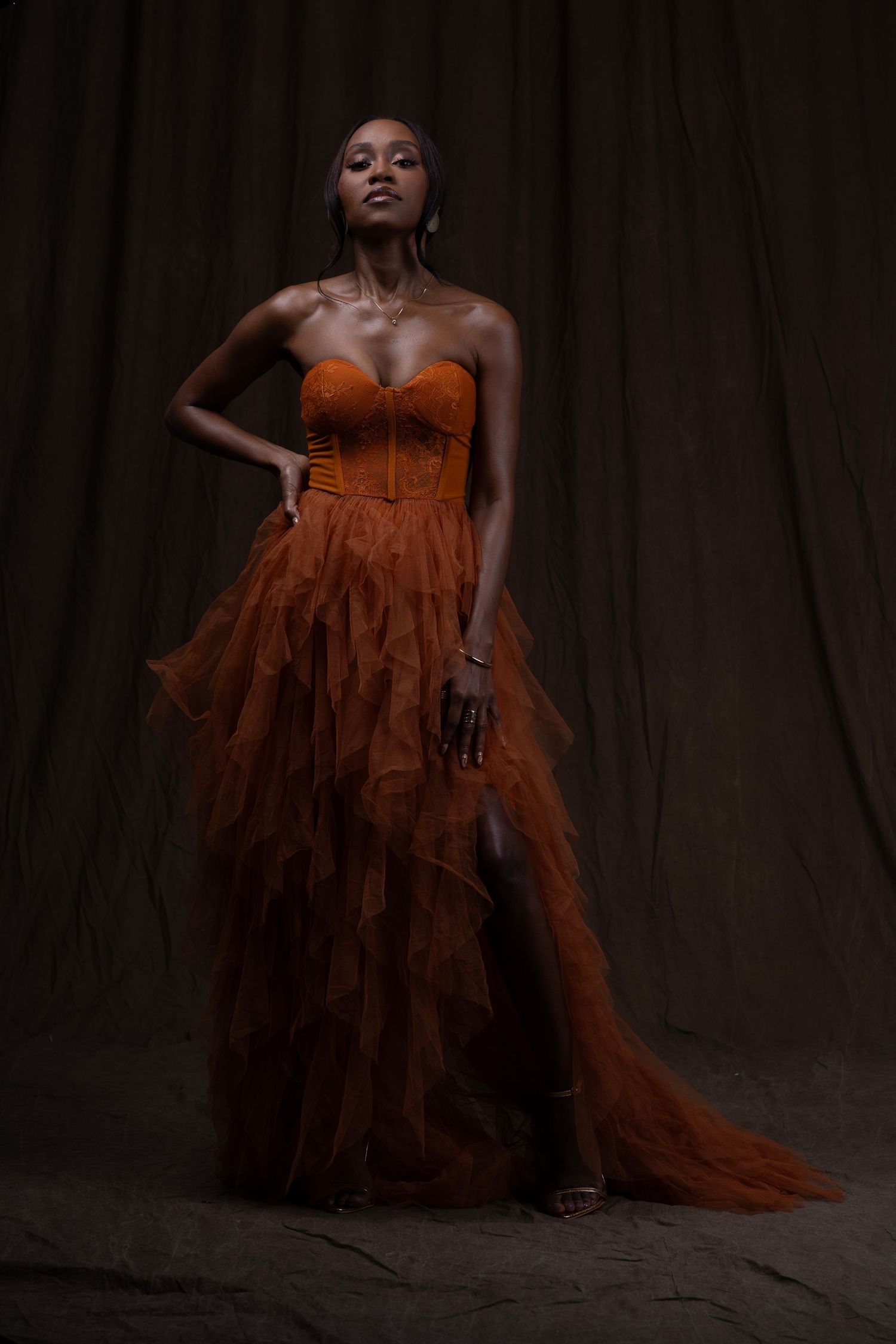 Dramatic fashion photos featuring a flowing rust-colored gown against a dark backdrop in Saint Petersburg Florida.