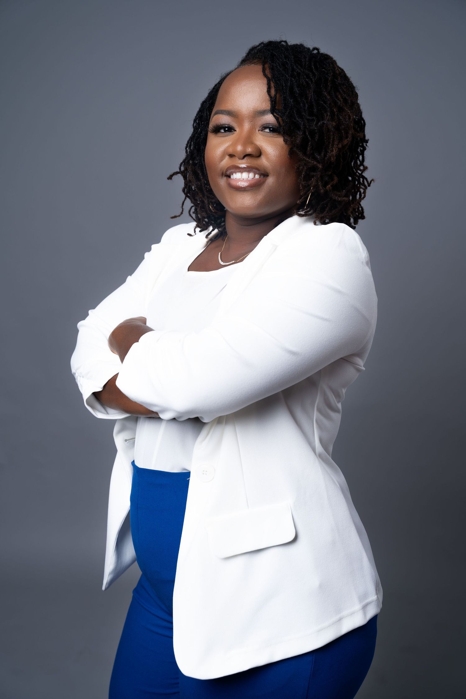 Professional studio portrait in white blazer and royal blue outfit against grey backdrop in Saint Petersburg Florida.