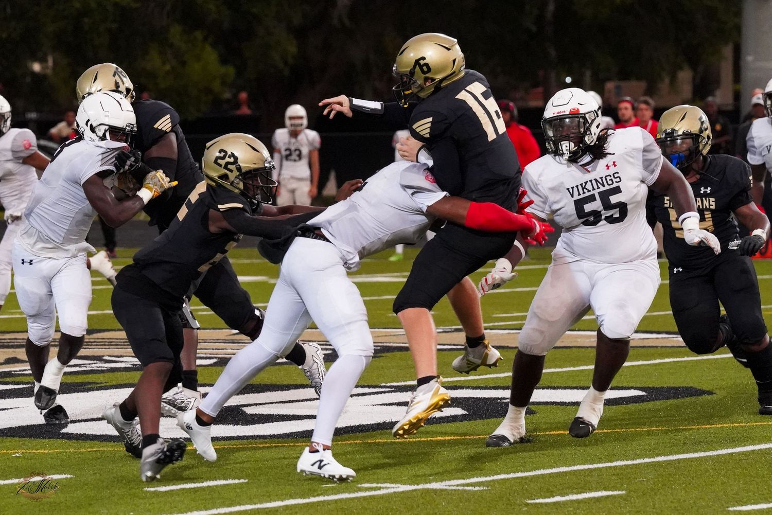 Football players in black and white uniforms clash during an intense college football game on a green field.