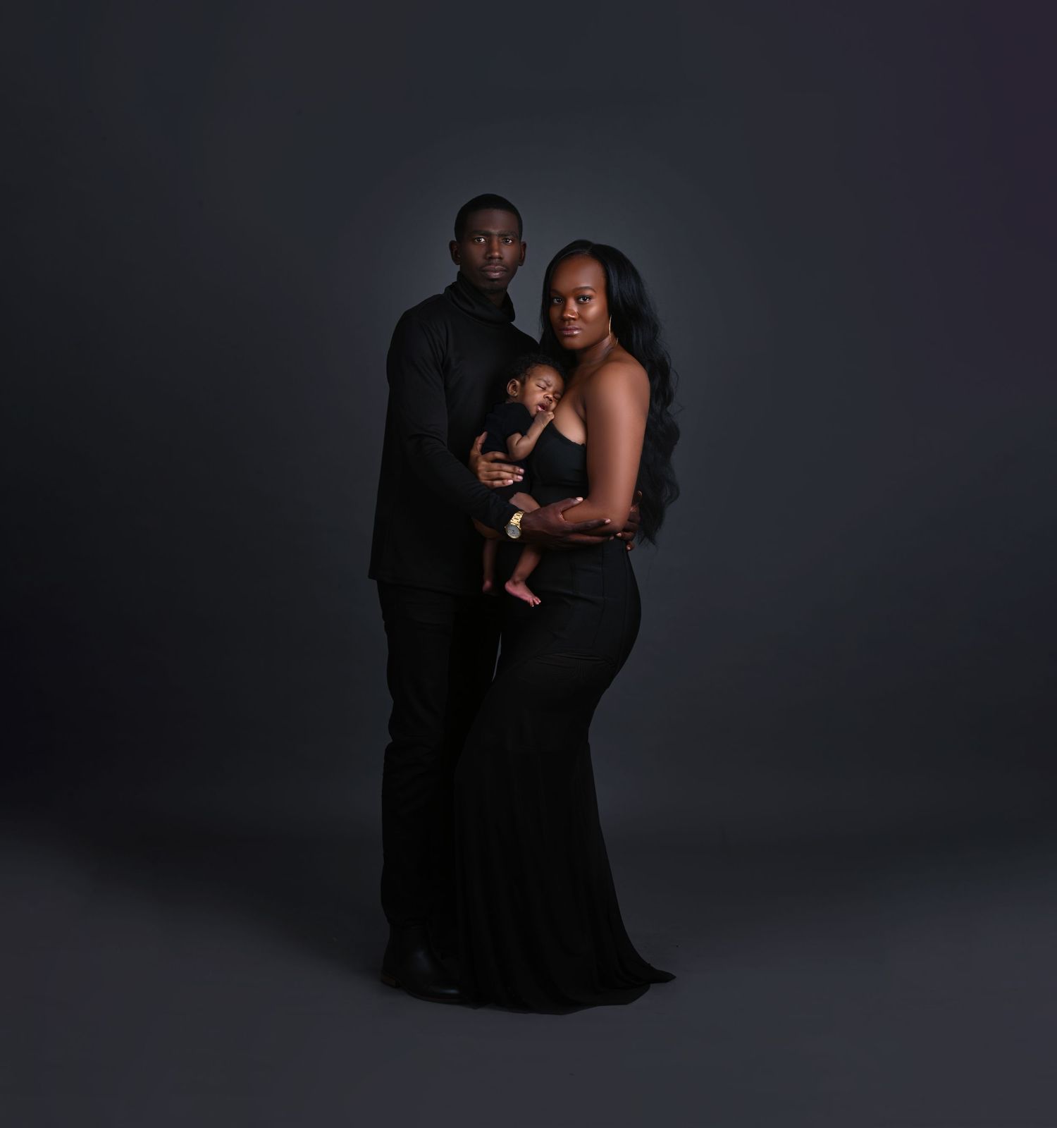 Dramatic low-key maternity photos of couple in dark studio setting.