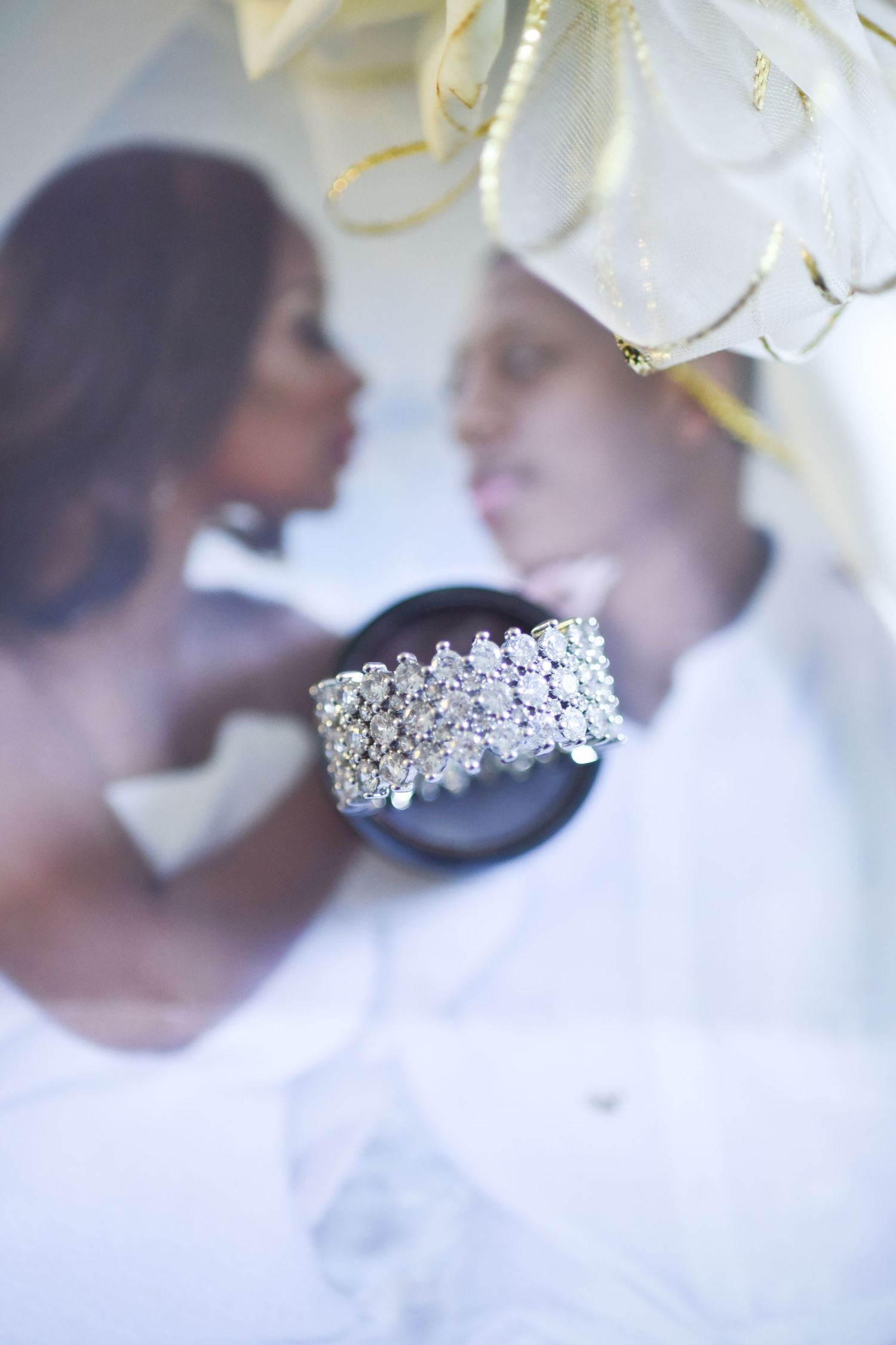 Diamond wedding band details with soft focus floral background.