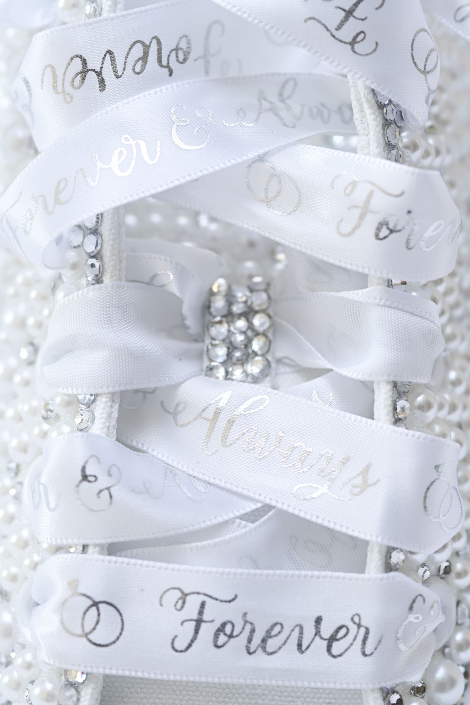 White satin ribbons with 'Forever' text and pearl decorations for wedding decor.