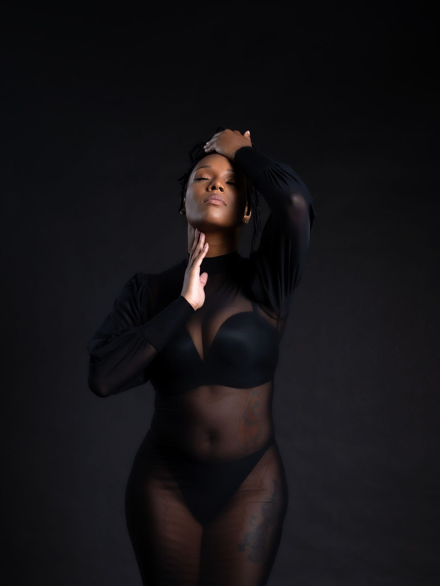 Artistic boudoir photo featuring silhouette in black lingerie against dark background in Saint Petersburg Florida.