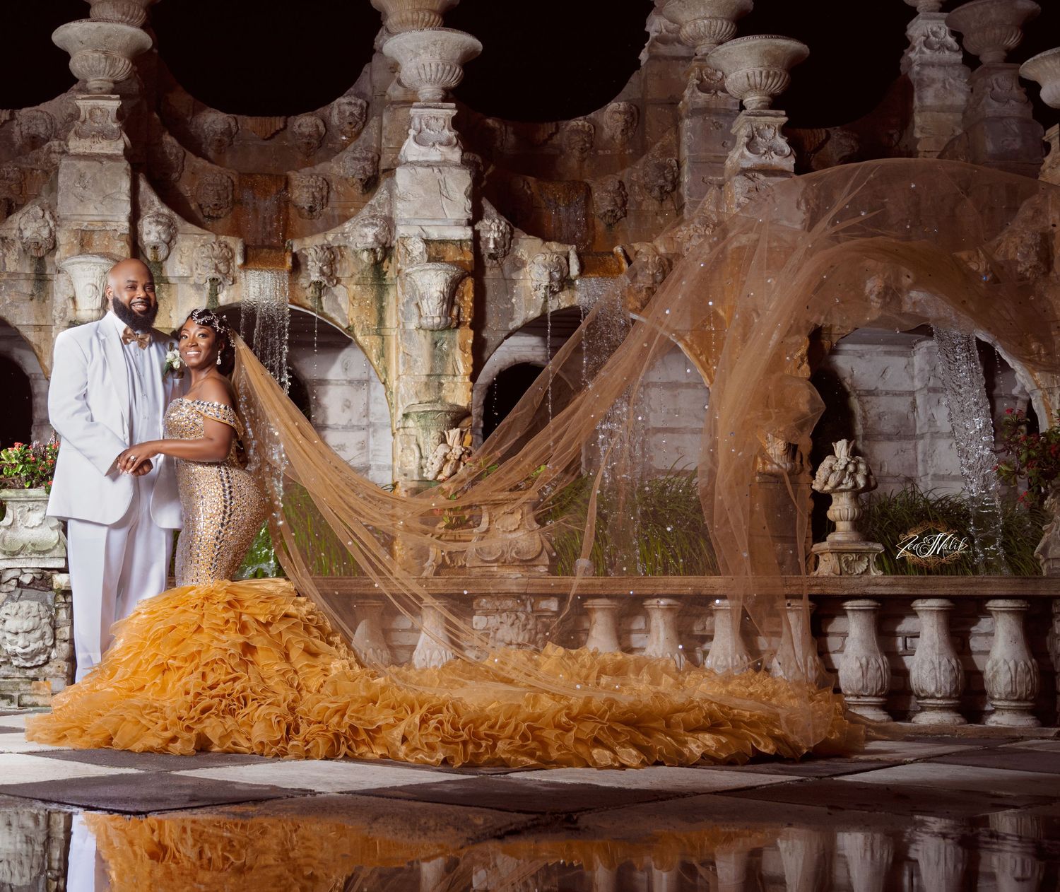 Dramatic wedding dress with long flowing train displayed in ornate stone architecture setting.