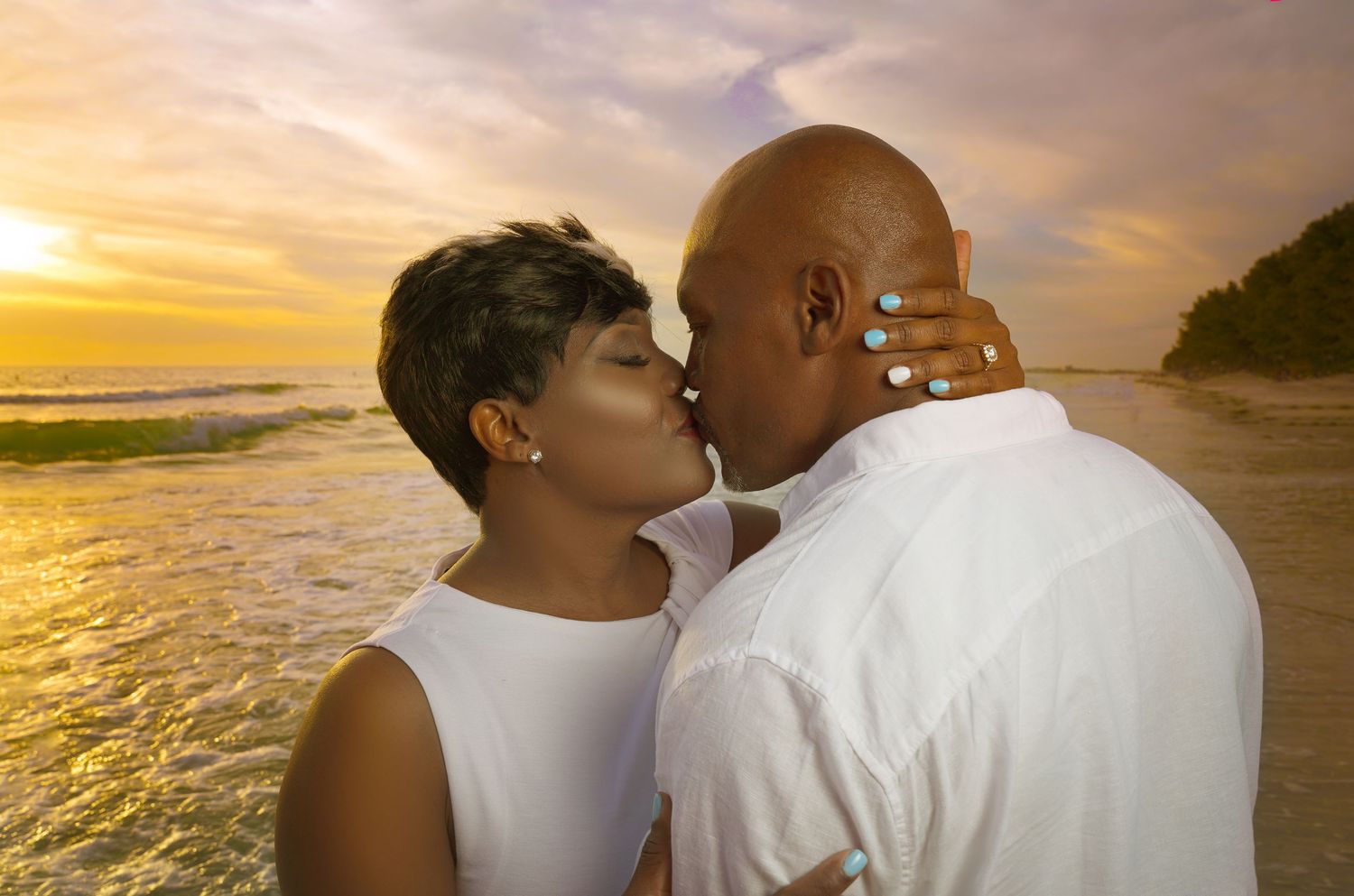 Romantic beach sunset photoshoot with golden light illuminating the couple.