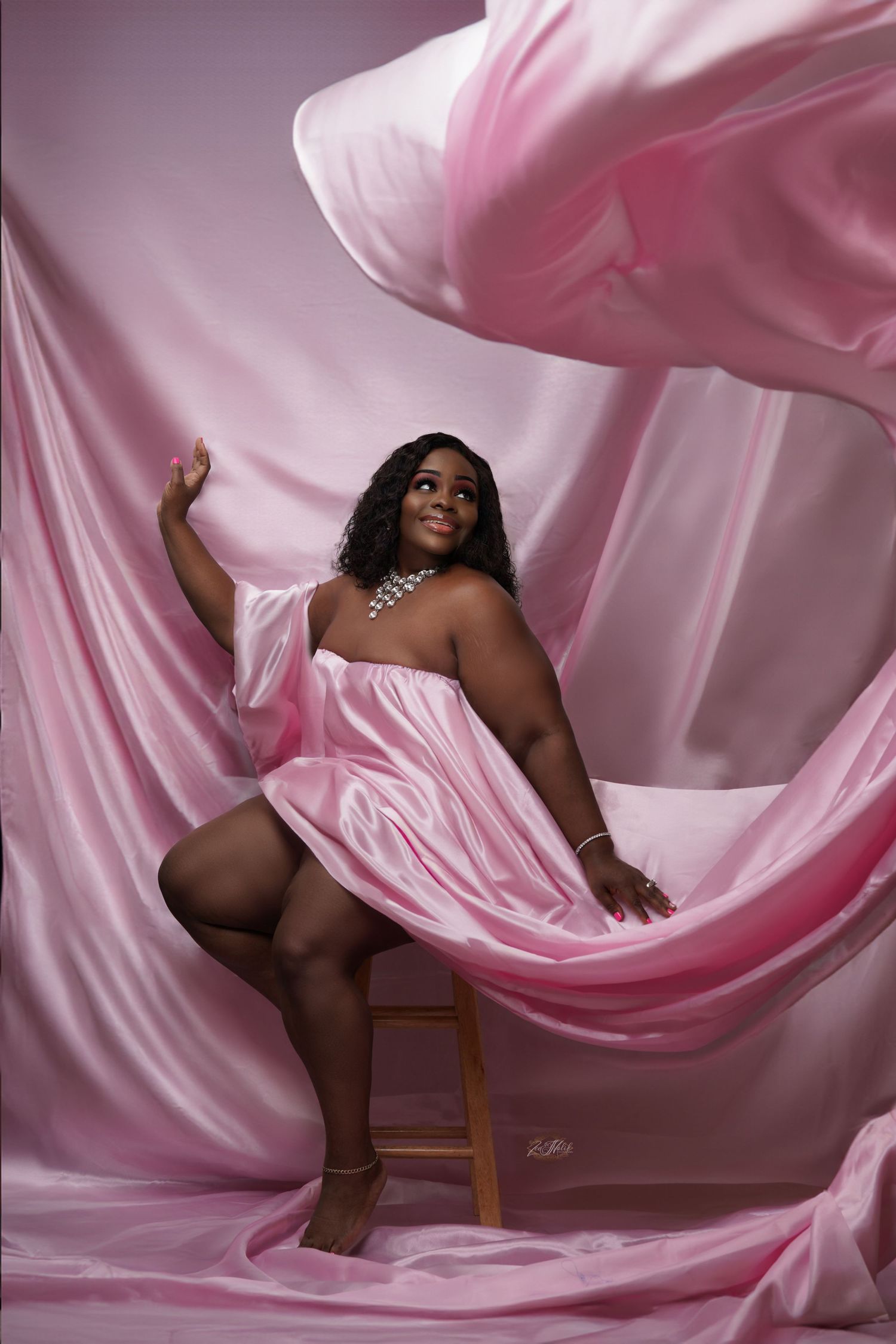 Artistic Full figured boudoir photoshoot with flowing pink satin fabric creating soft romantic atmosphere in Saint Petersburg Florida.