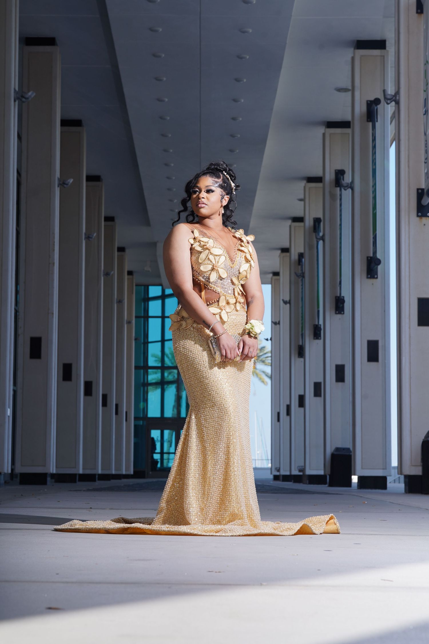 A figure in a flowing gold sequined gown poses gracefully in an elegant architectural space with columns in Saint Petersburg Florida.